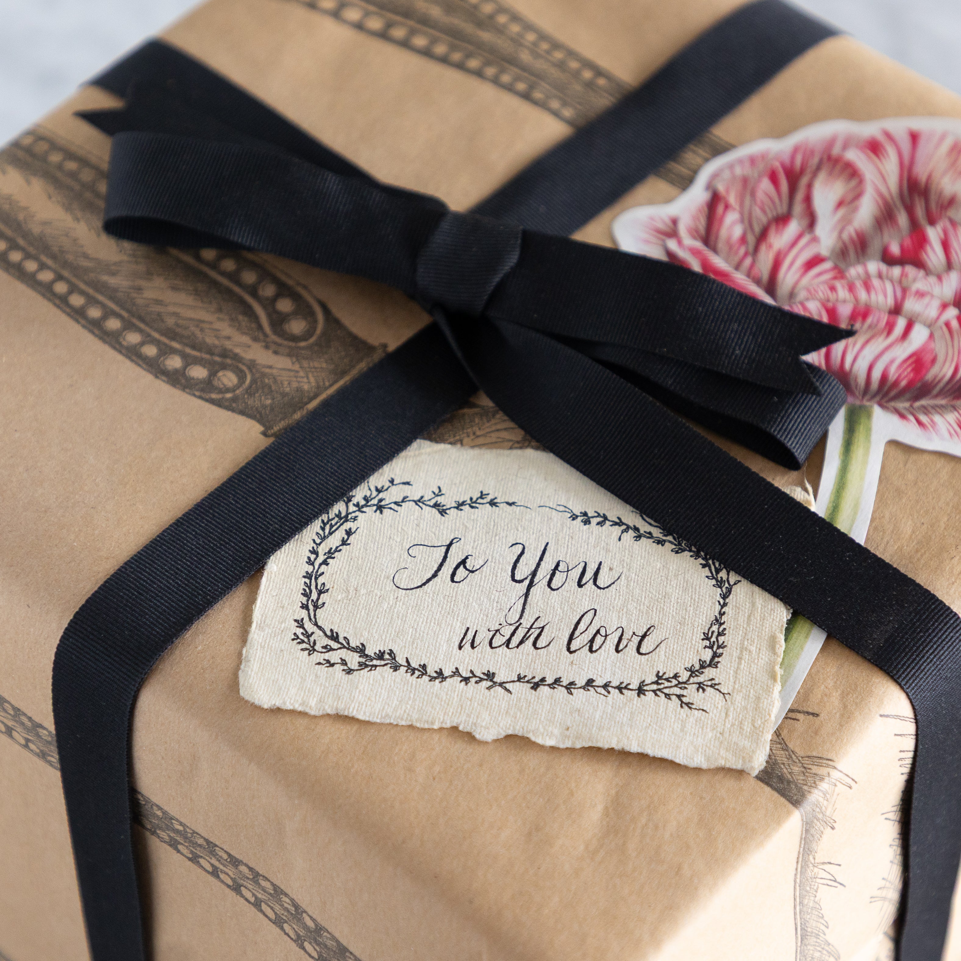 Gift wrapped in Cutlery on Kraft Runner tied with a black ribbon and &