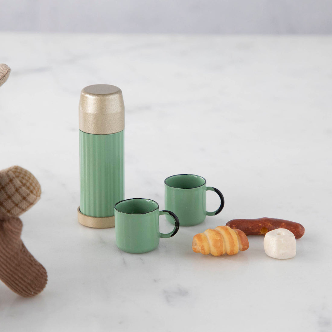 A teddy bear sits next to a Maileg Mini Thermos and Cups Set.