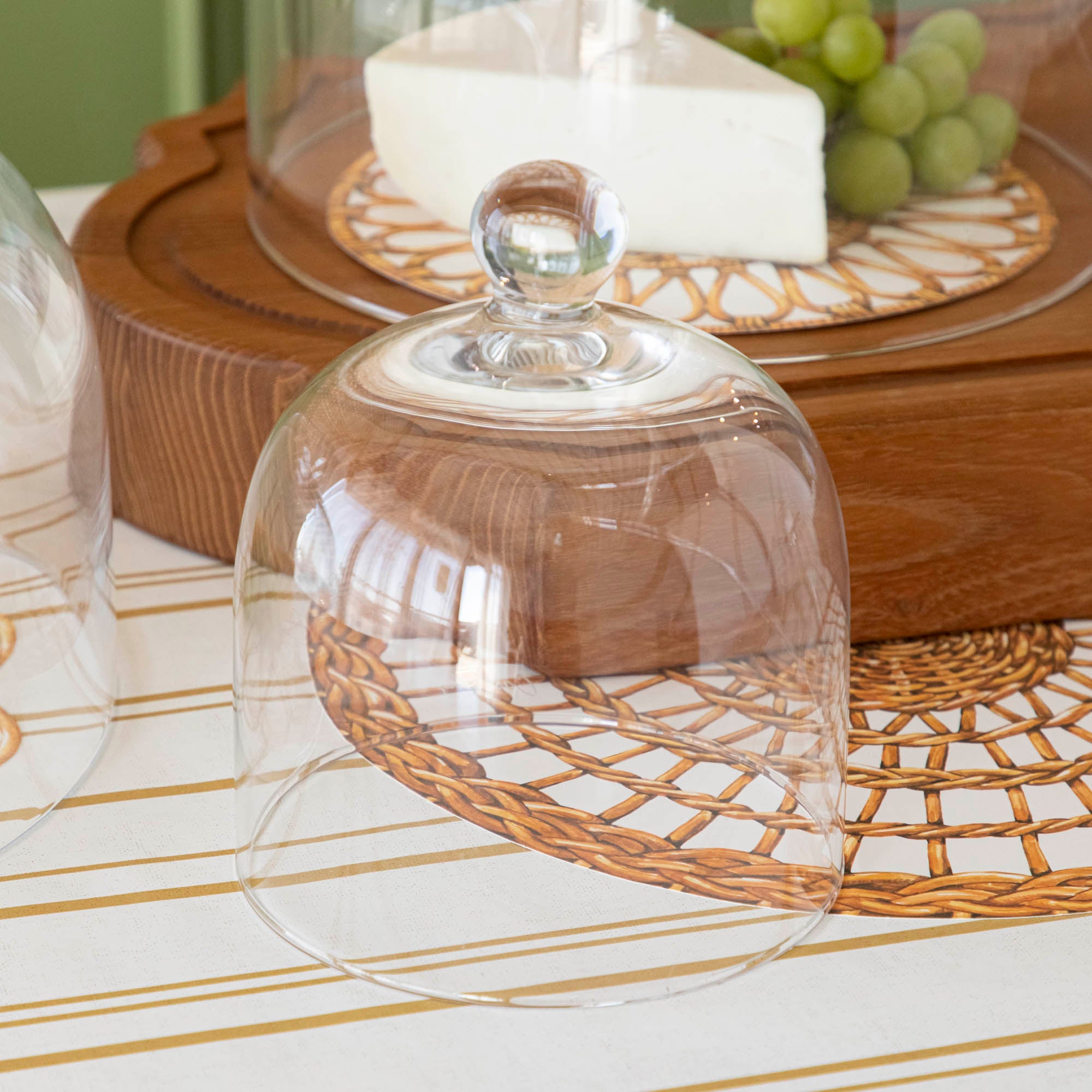 Various cheeses and grapes displayed under a Casafina Living glass dome serveware on a kitchen counter.