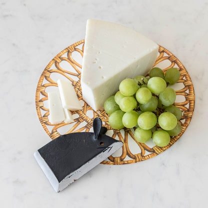 A plate with a wedge of cheese, a bundle of green grapes, and a Magenta Wrought Iron Mouse Cheese Blade.