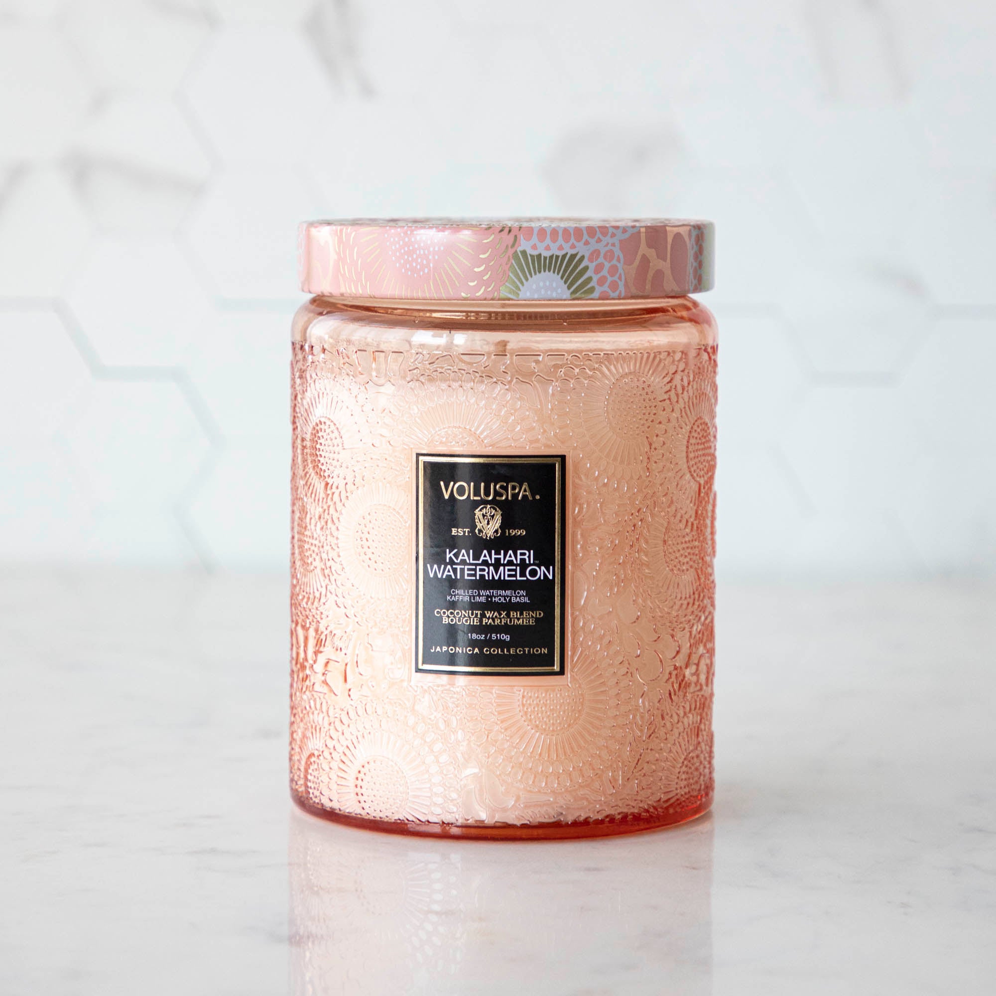 Two Voluspa Kalahari Watermelon candles on a marble surface with matches nearby, featuring a crisp cucumber aroma.