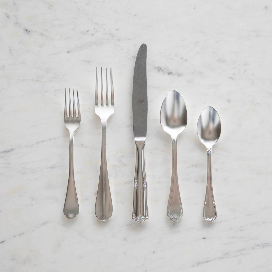 A Mepra Original Vintage 5-Piece Place Setting, including two forks, a knife, and two spoons, arranged on a marble surface.