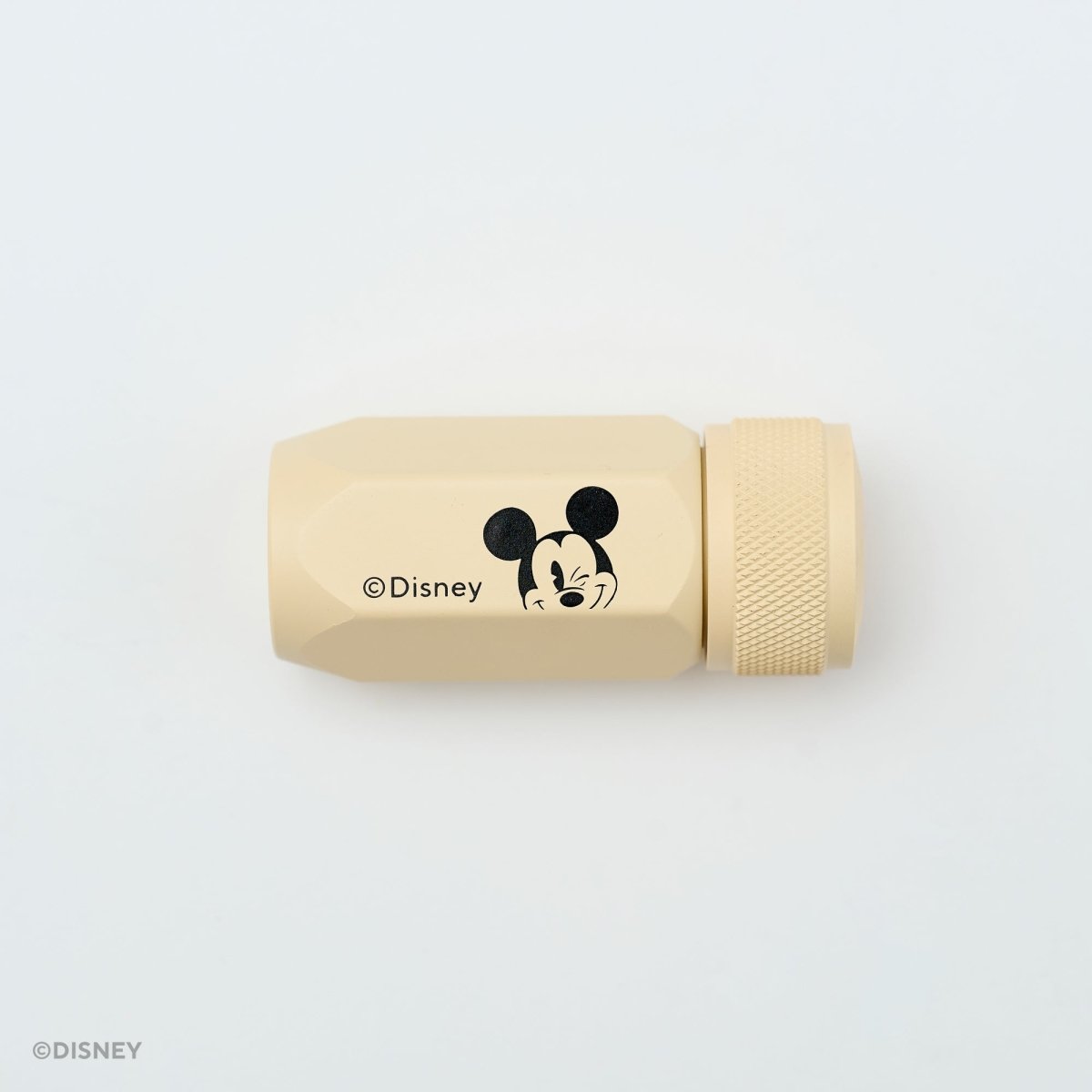 A beige cylindrical Disney pencil sharpener with a black Mickey Mouse face graphic and the Disney copyright text, shown on a clean white background.