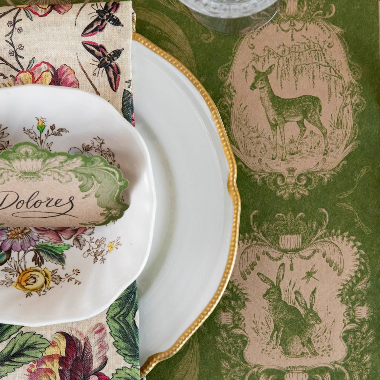 Close-up of the Moss Fable Toile Placemat under a place setting, showing the deer and two rabbits in detail.
