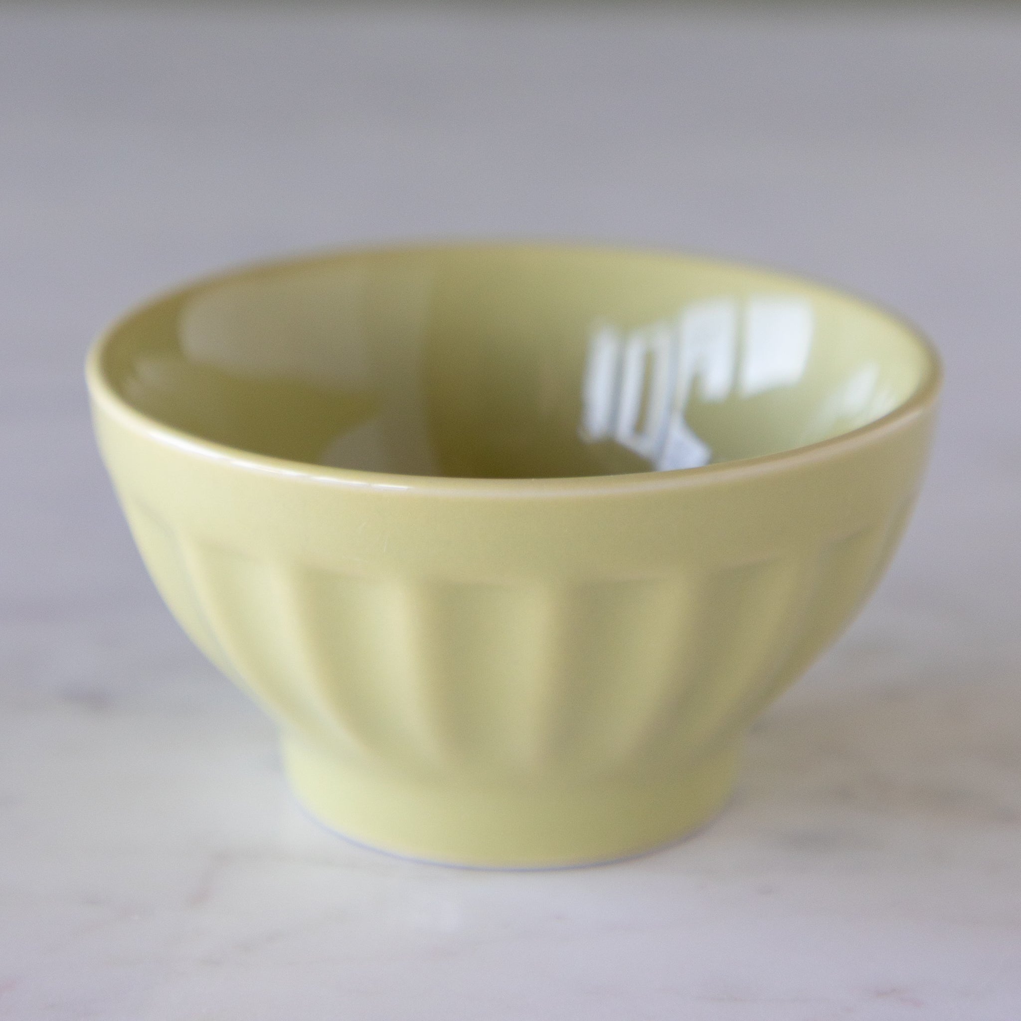 Pistachio colored ceramic pinch bowl on a marble table.