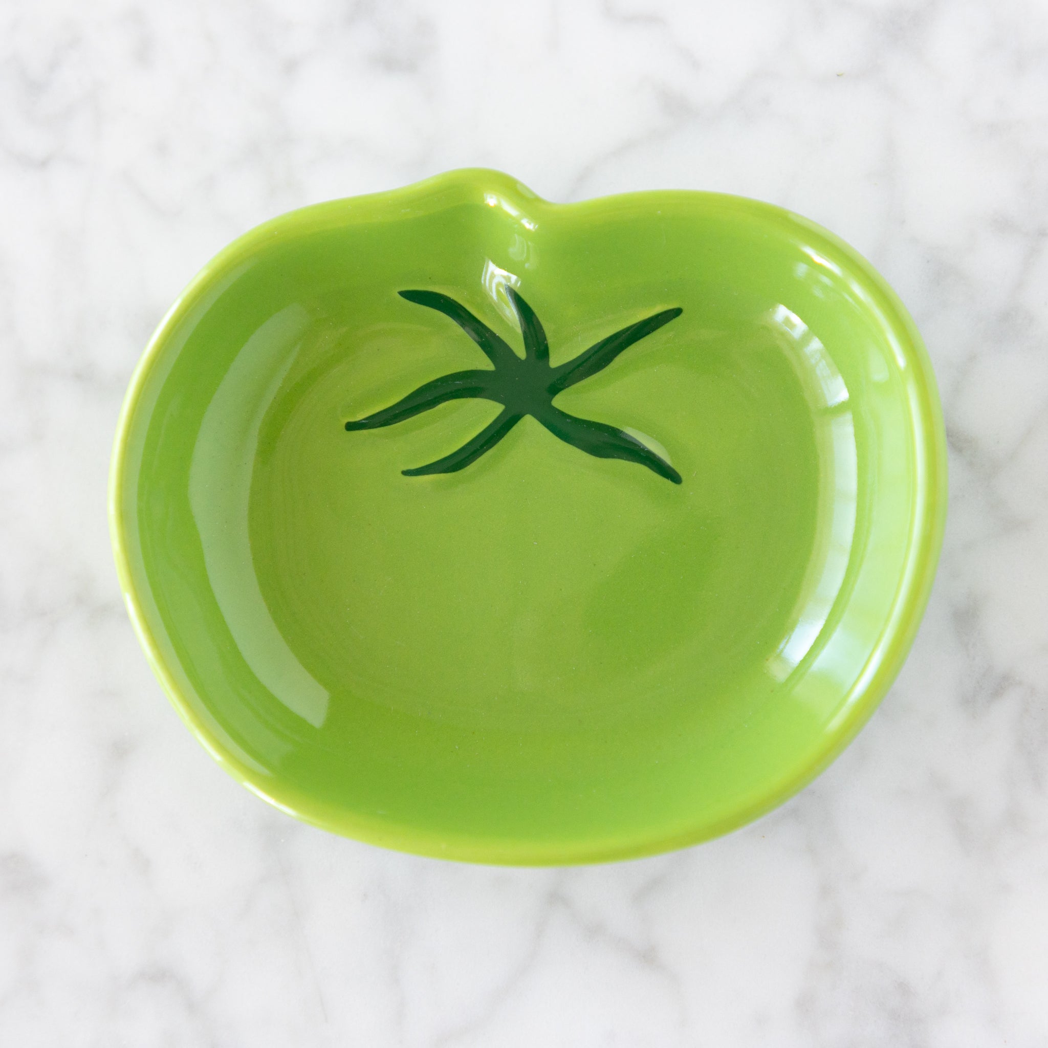 Green ceramic dish with a green stem design on a white textured background.