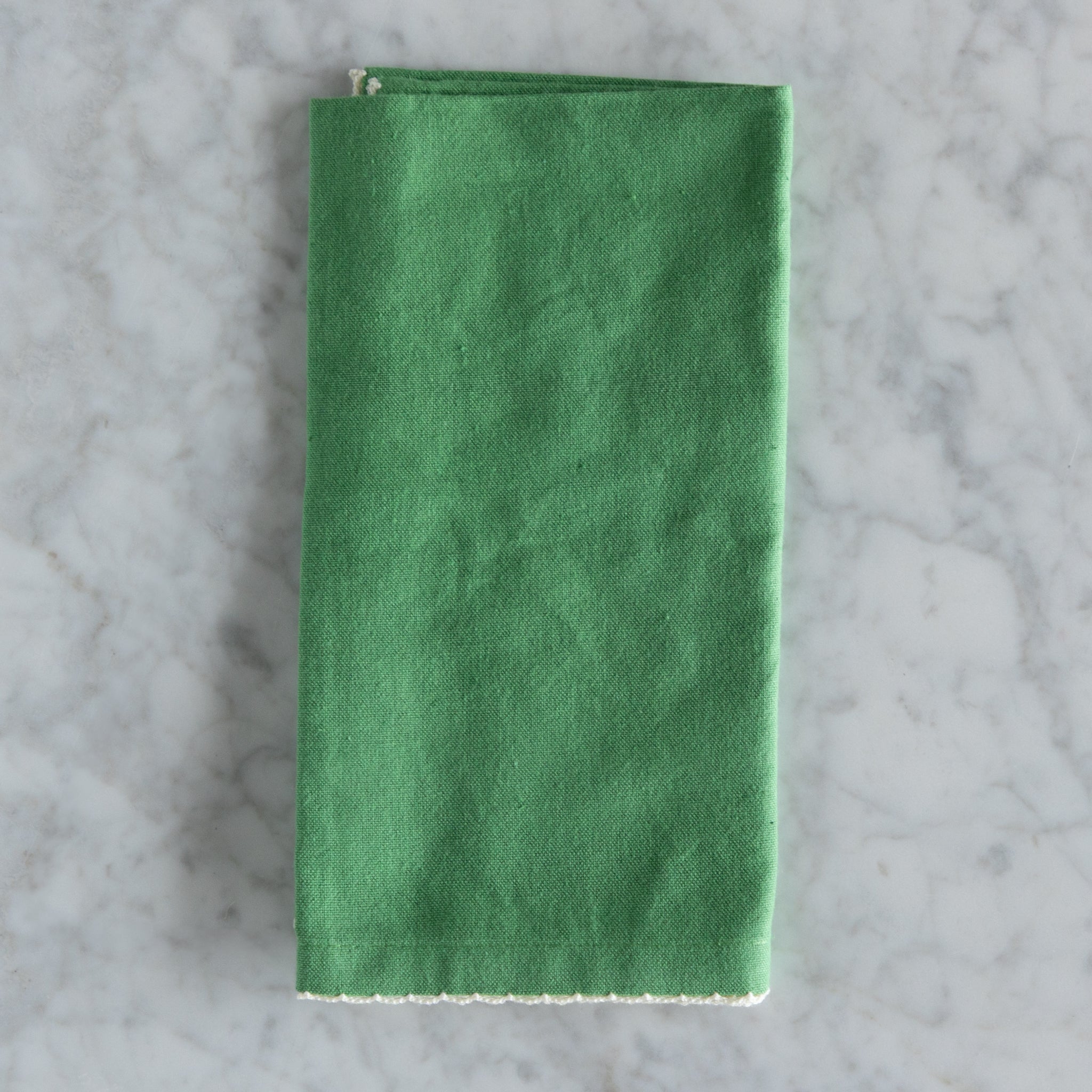 Green folded napkin on a gray marble surface.