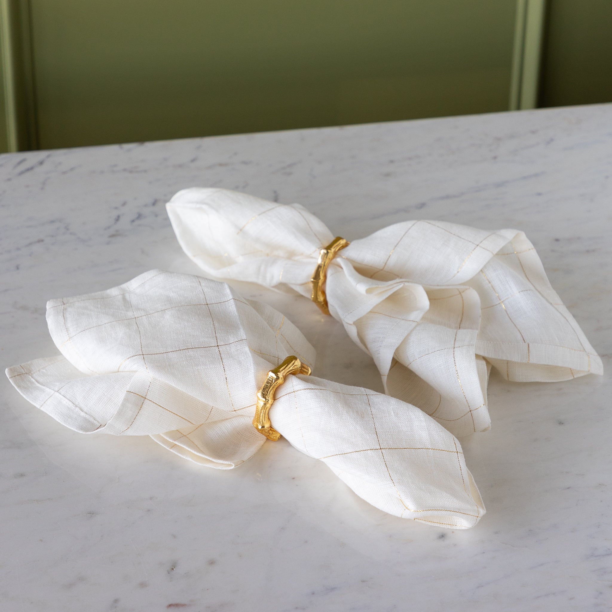 Aluminum Bamboo Napkin Rings around elegant white with gold stripes napkins.