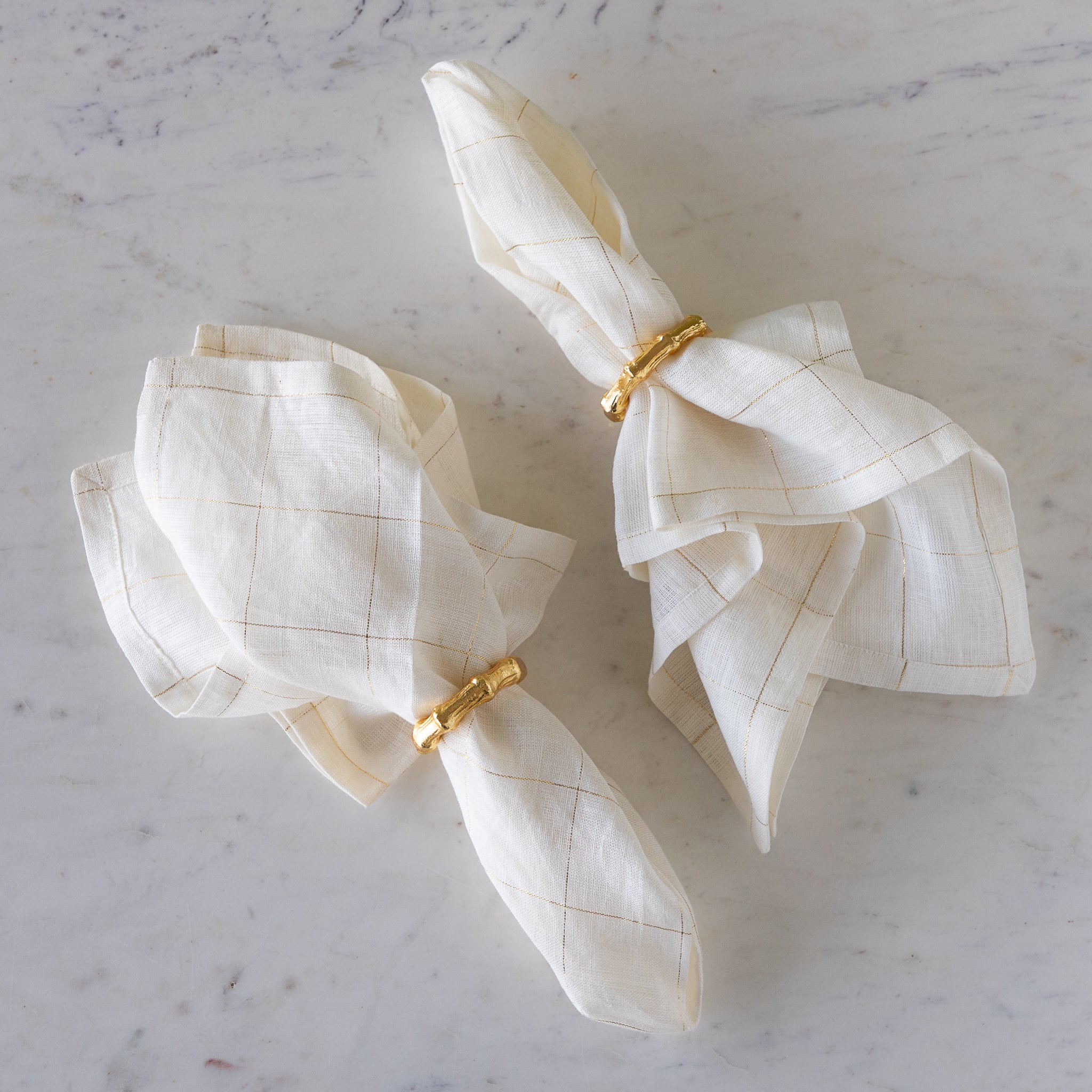 Aluminum Bamboo Napkin Rings around elegant white with gold stripes napkins.
