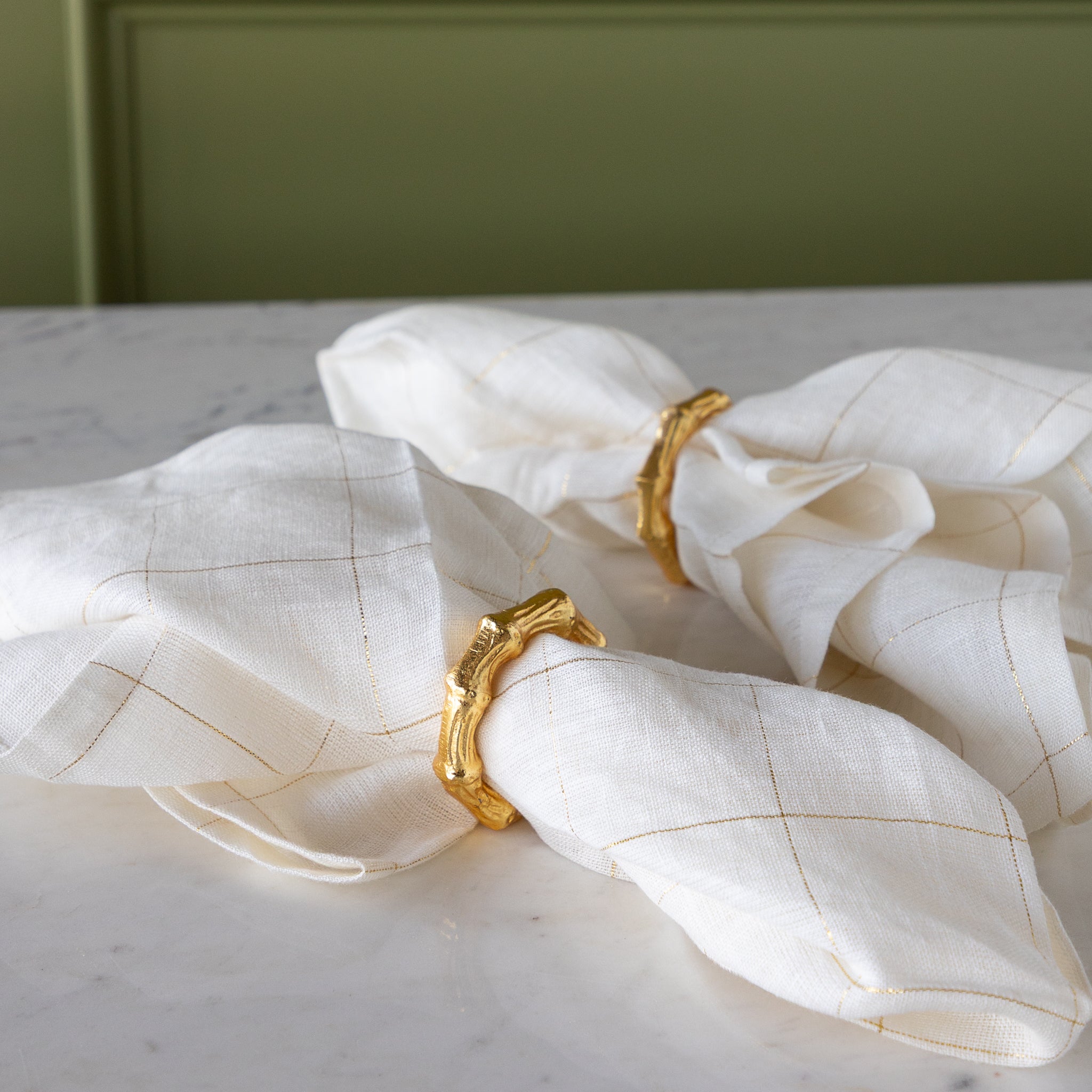 Aluminum Bamboo Napkin Rings around elegant white with gold stripes napkins.