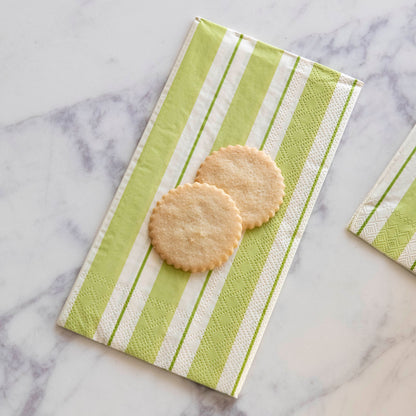 Two sugar cookies sitting on a Green Awning Stripe Guest Napkin on a white table.