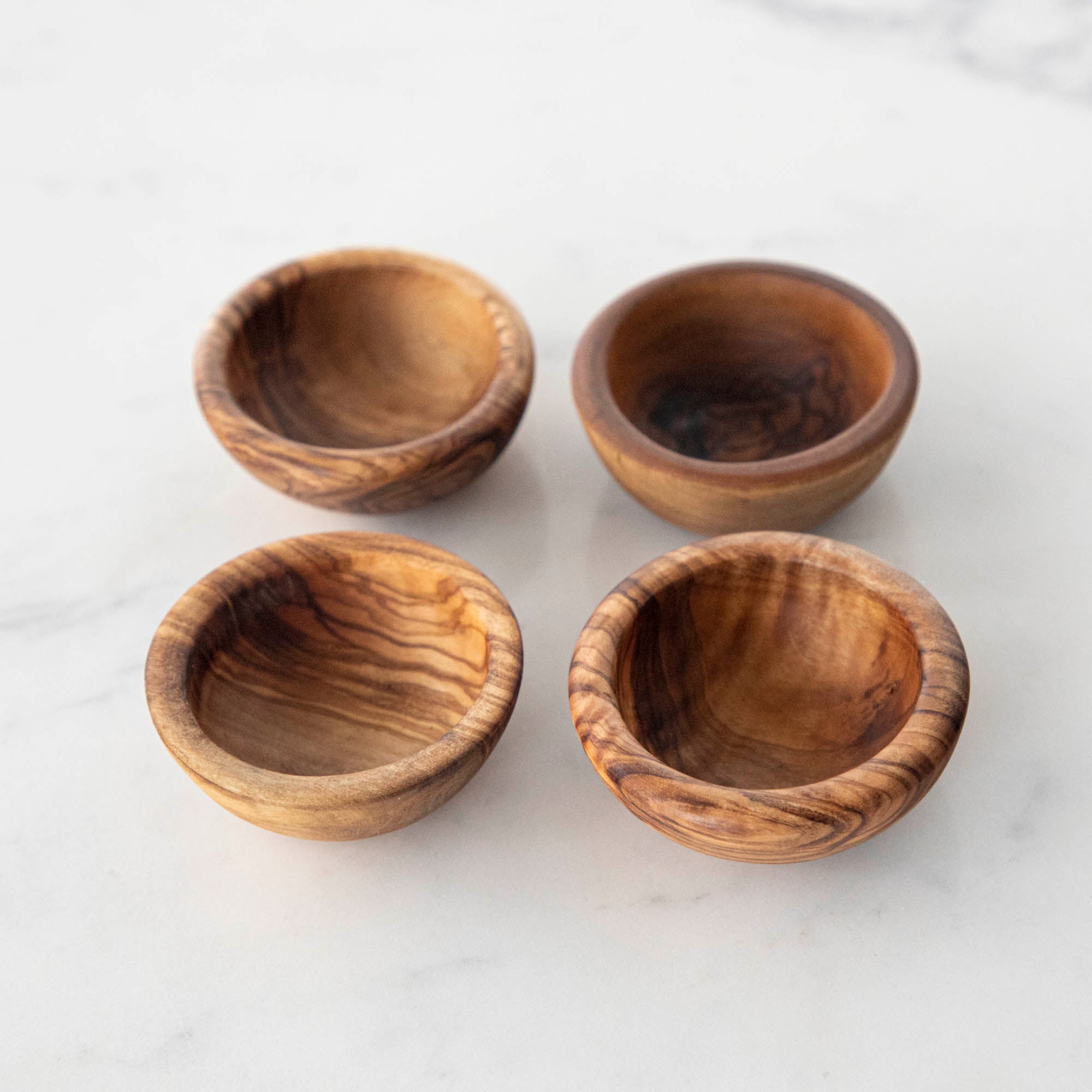 Four Natural Olivewood Pinch Bowls on a white table.