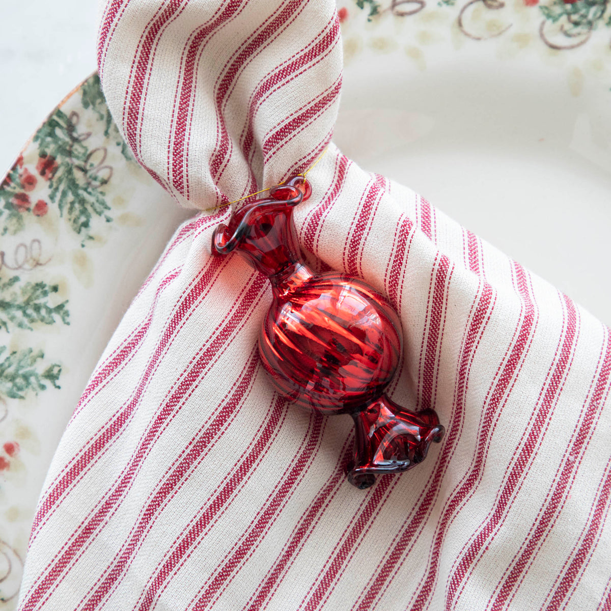 Close up of the Red Round Candy Shaped Ornament tied to a red striped napkin