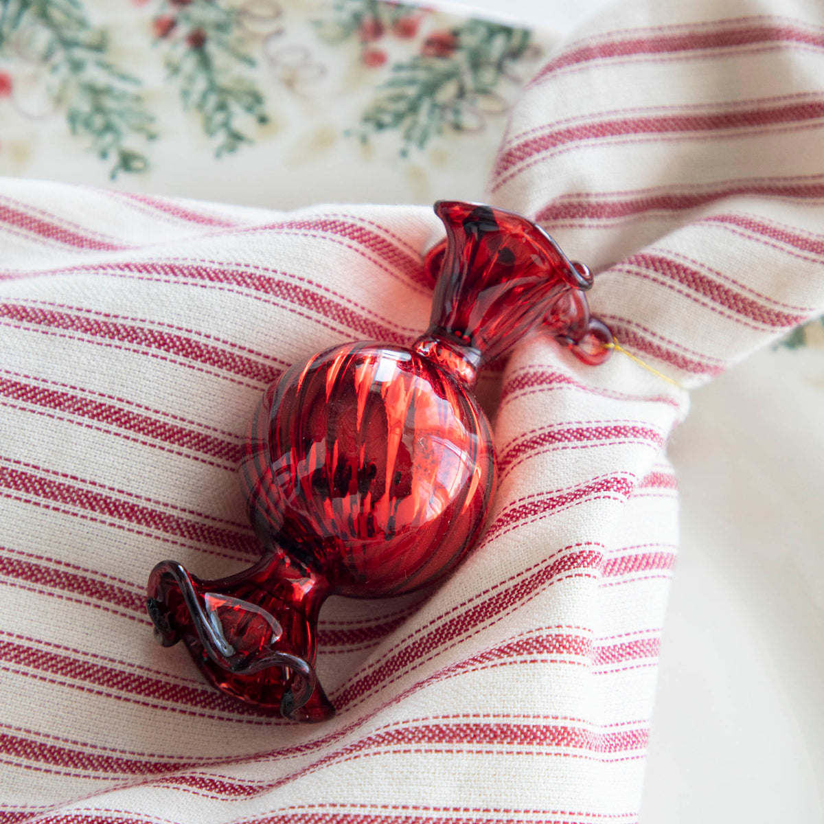 Close up of the Red Round Candy Shaped Ornament tied to a red striped napkin