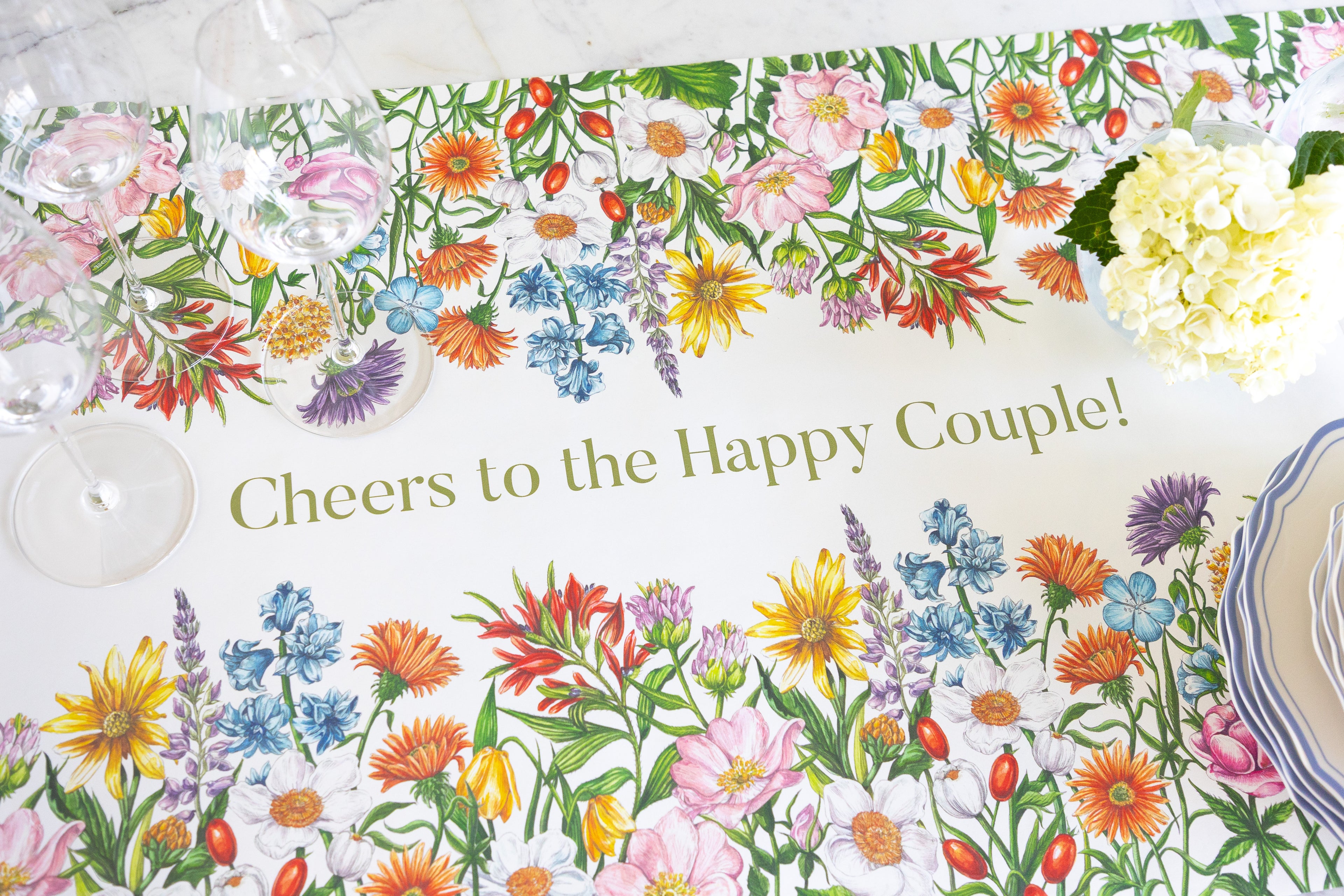 A white table runner printed with a colorful wildflower border and the phrase &