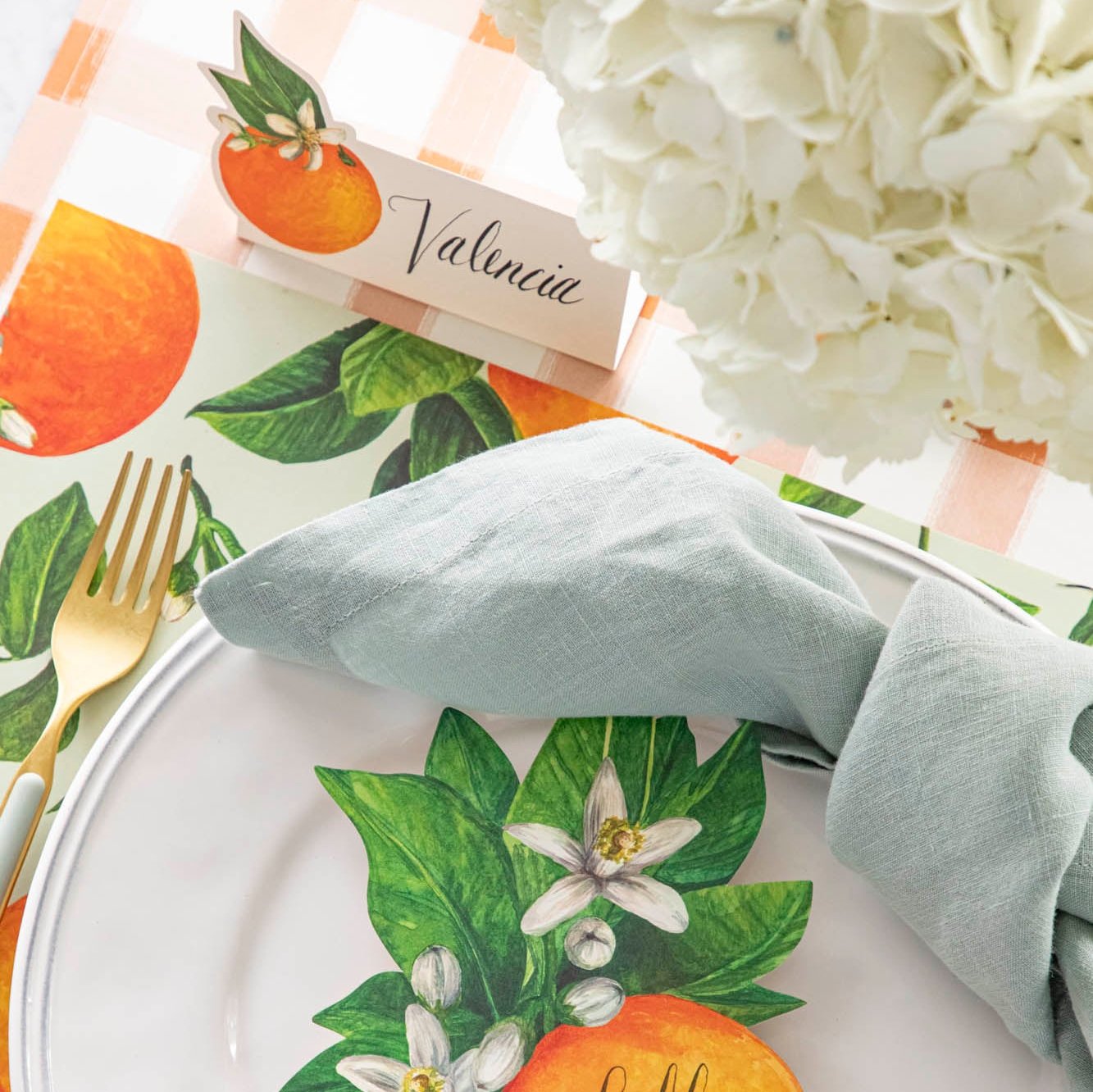 An elegant, citrus-themed table setting with the Orange Blossom Place Card that has the name "Valencia" written on it.
