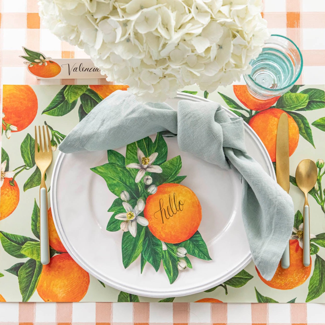An elegant table setting featuring the Orange Orchard Placemat and Orange Table Accent resting on a dinner plate.
