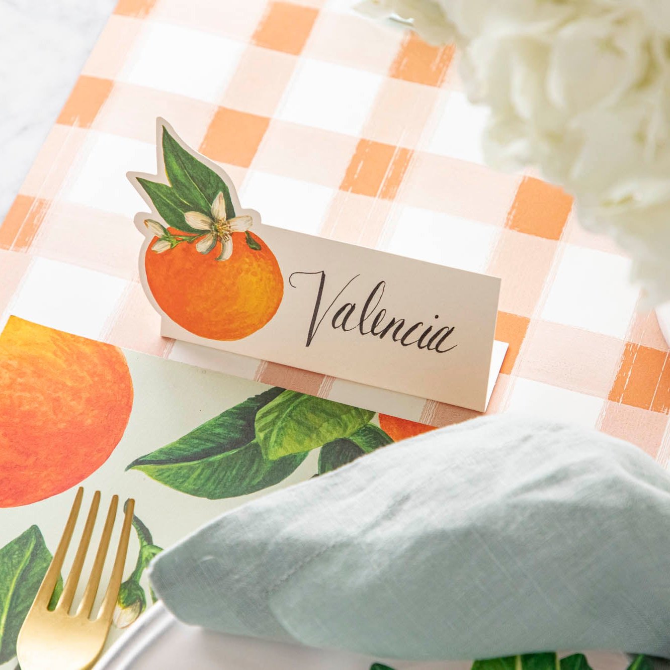 The Orange Blossom Place Card with "Valencia" written on it, on the Orange Painted Check Runner.