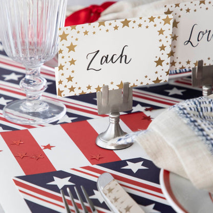 Close-up of a Shining Star Place Card labeled &quot;Zach&quot; held up by a silver place card holder on a patriotic table setting.