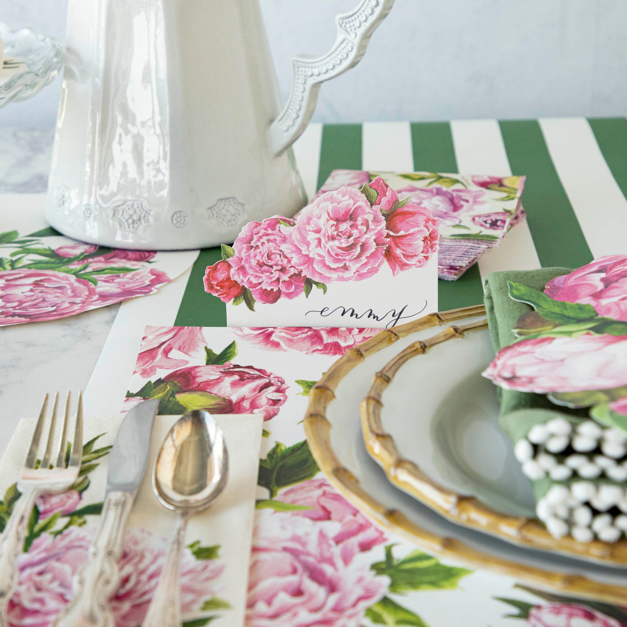 An elegant place setting featuring a Peony Place Card labeled "Emmy" standing behind the plate.