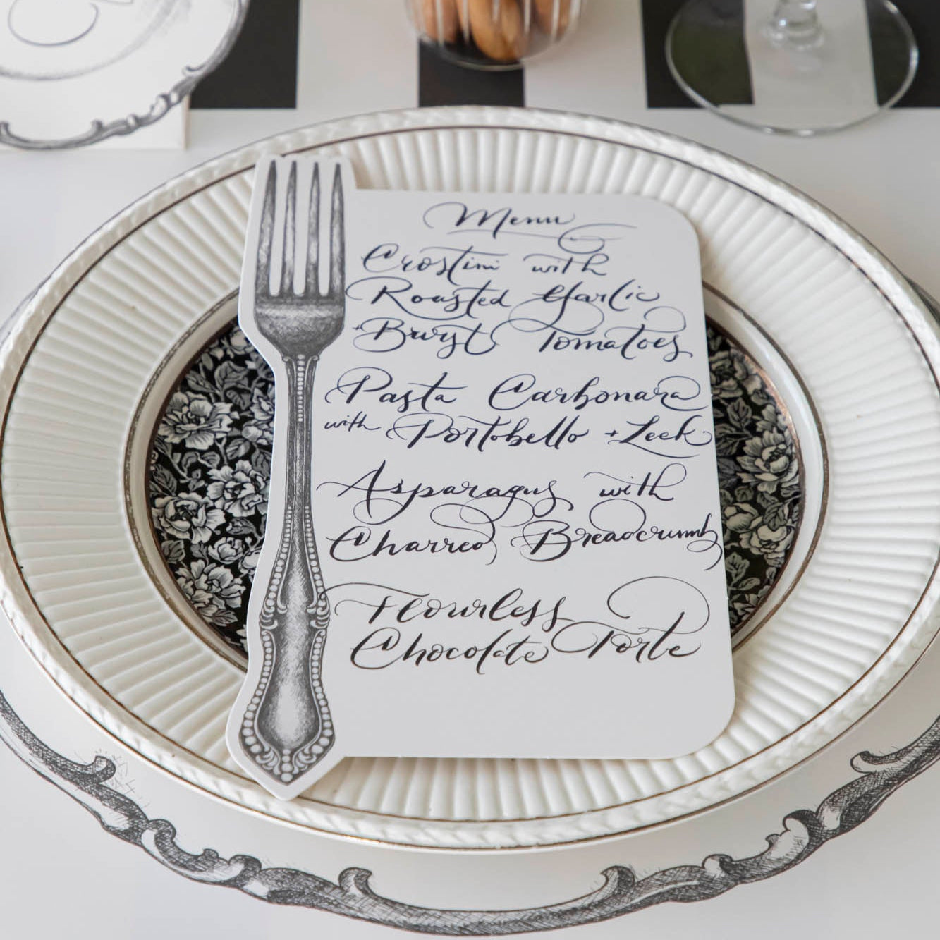Vintage Fork Table Card with a menu written on it, resting on dinner plates on a table setting for one.