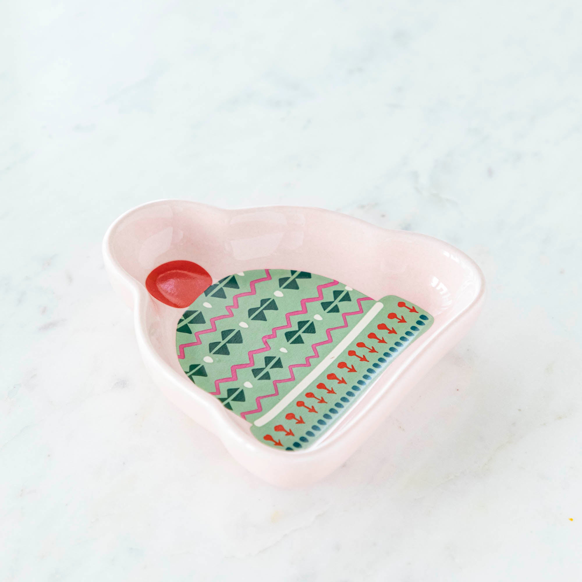 A stoneware pinch bowl with a beanie shape featuring a Christmas-themed pattern.