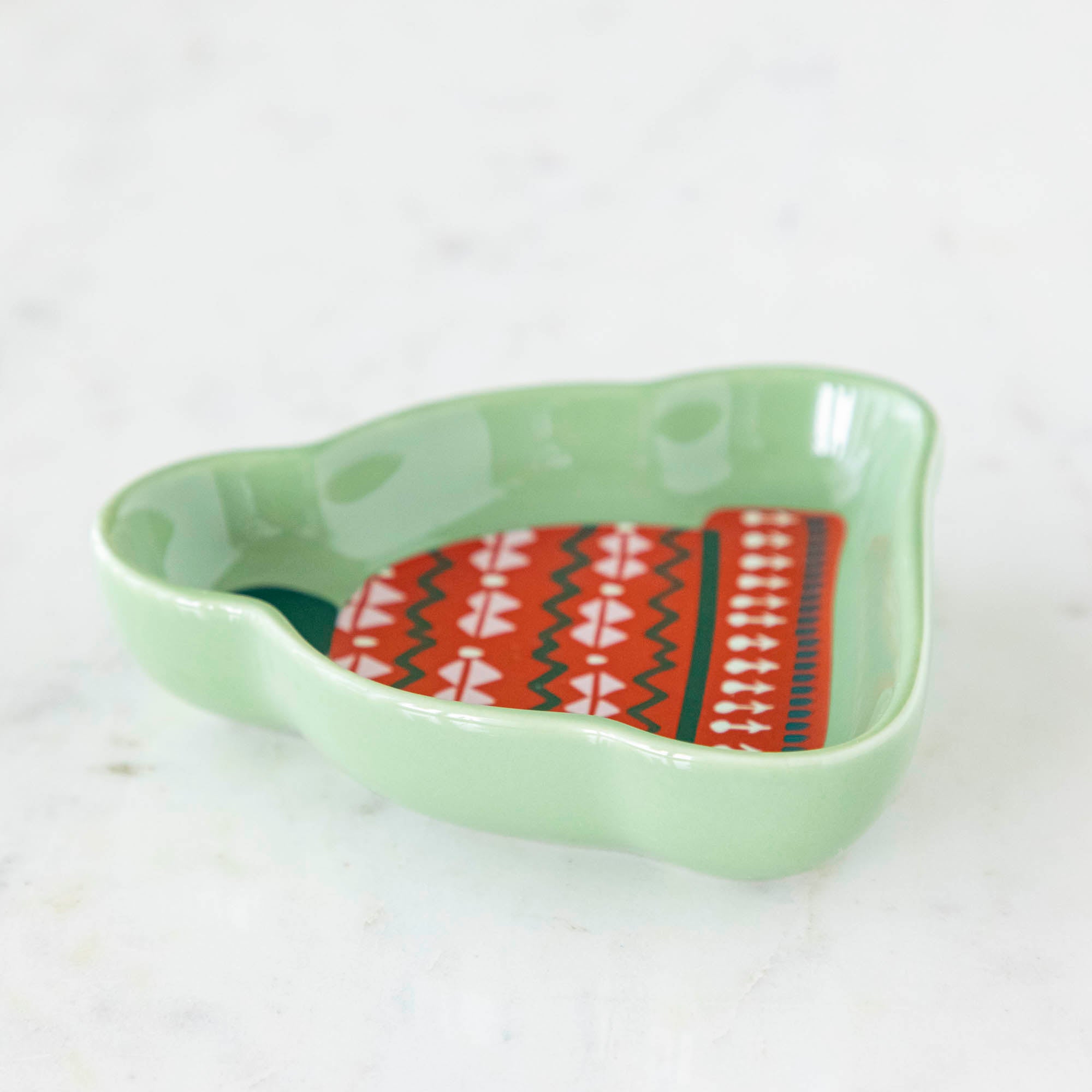 A stoneware pinch bowl with a beanie shape featuring a Christmas-themed pattern.