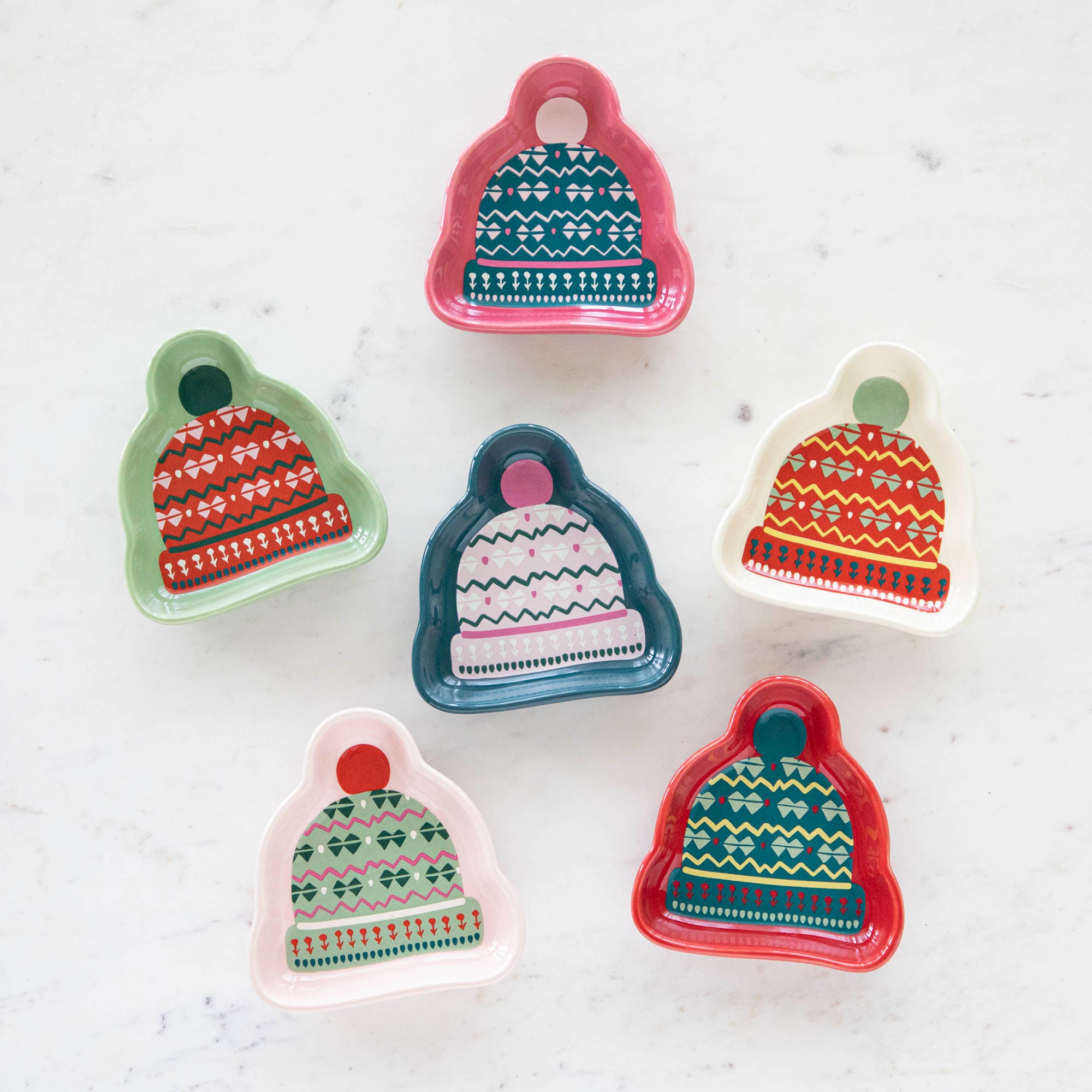 A set of stoneware pinch bowls with a beanie shape, featuring various Christmas-themed patterns in red, green, and white colors.