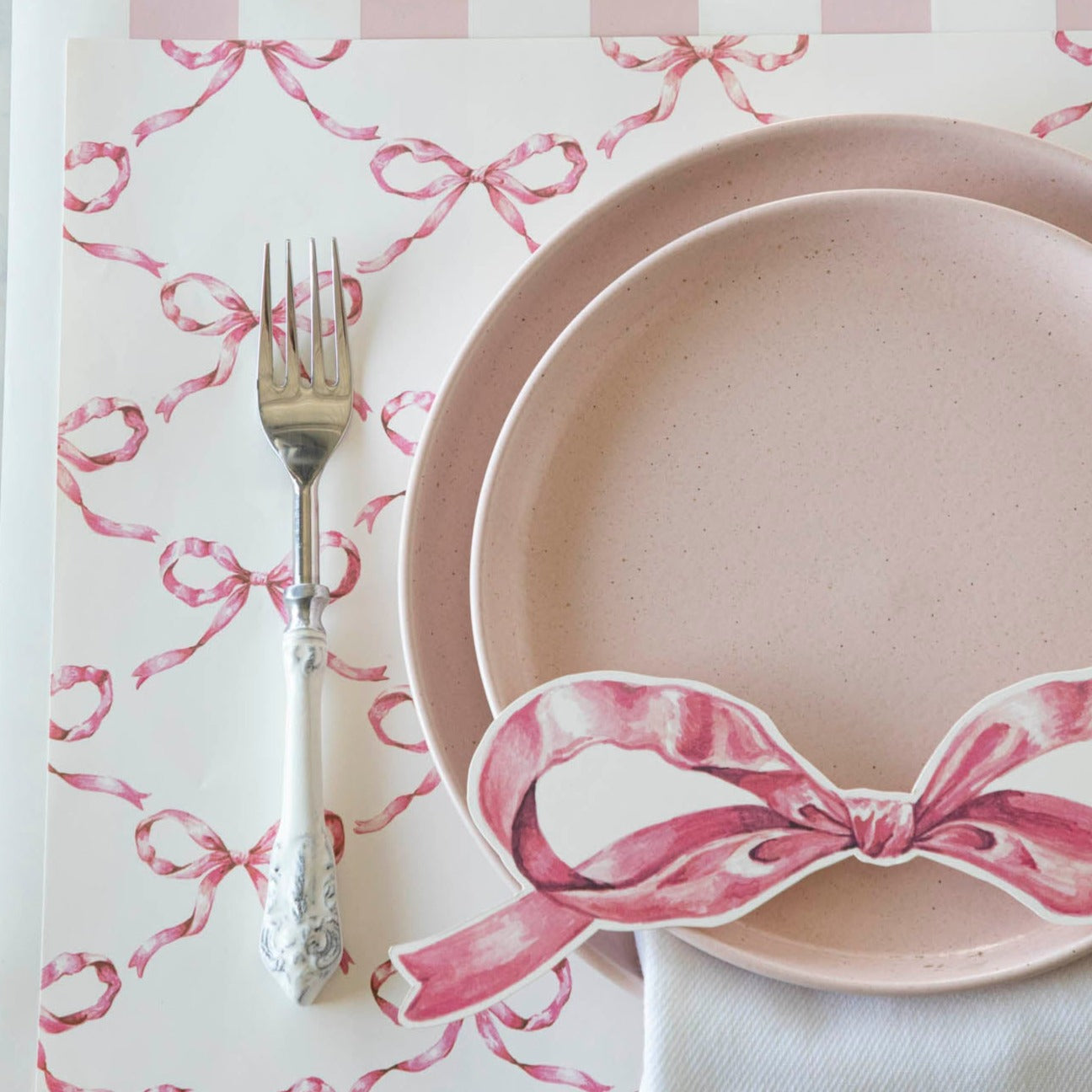 An elegant place setting featuring a Pink Bow Table Accent resting on the plate.