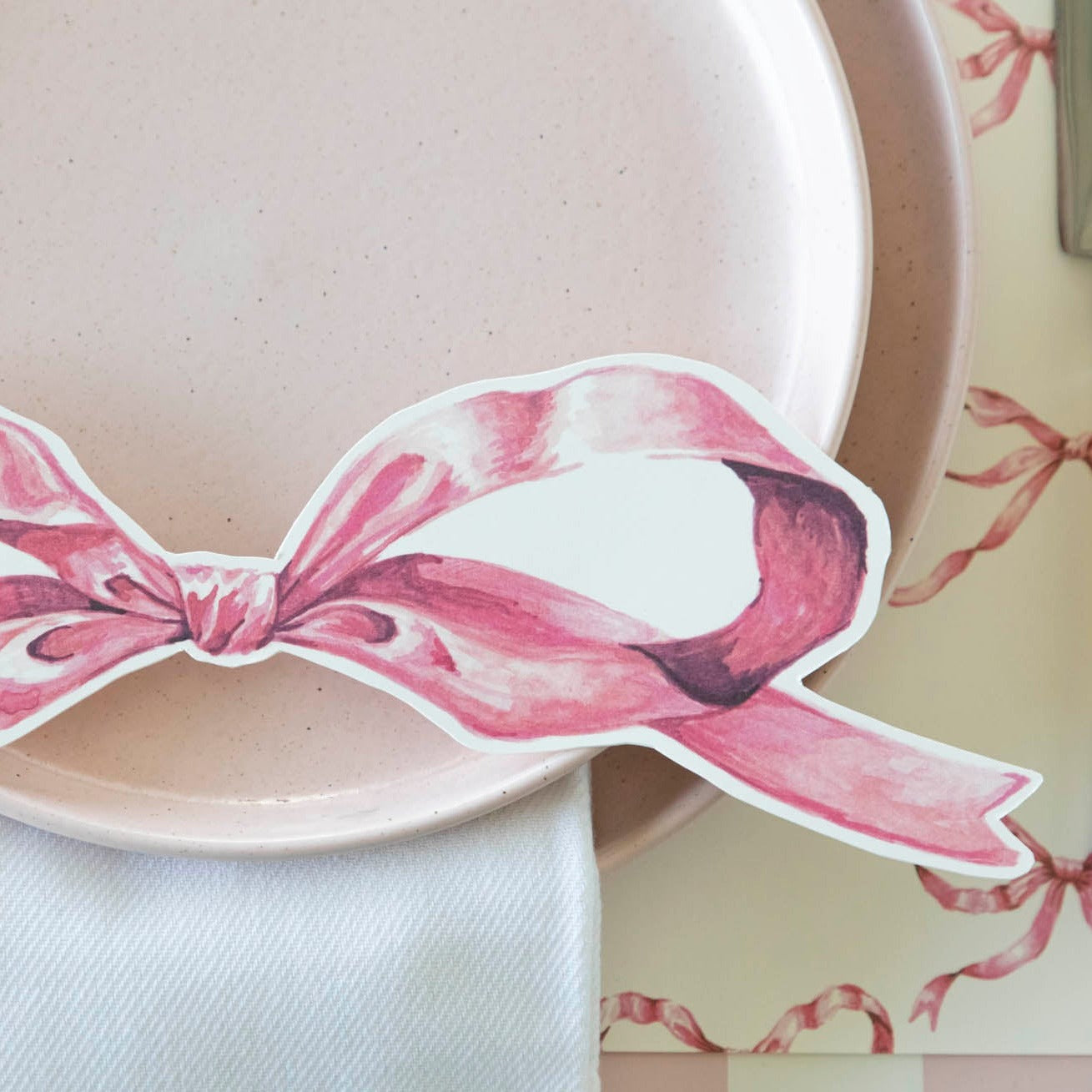 Close-up of an elegant place setting featuring a Pink Bow Table Accent resting on the plate.