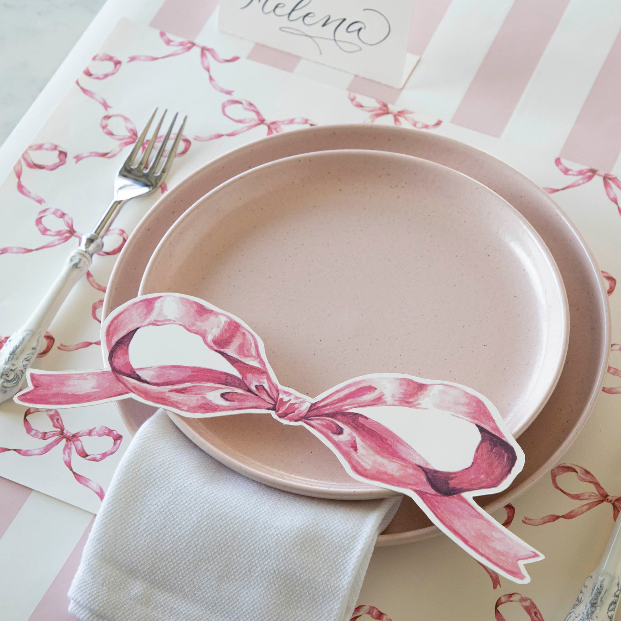 An elegant place setting featuring a Pink Bow Table Accent resting on the plate.