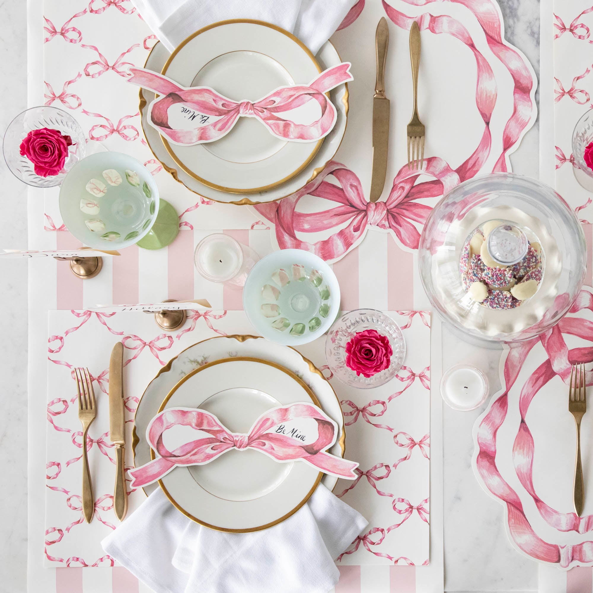 Top-down view of an elegant pink bow table setting featuring a Pink Bow Table Accent resting on each plate.