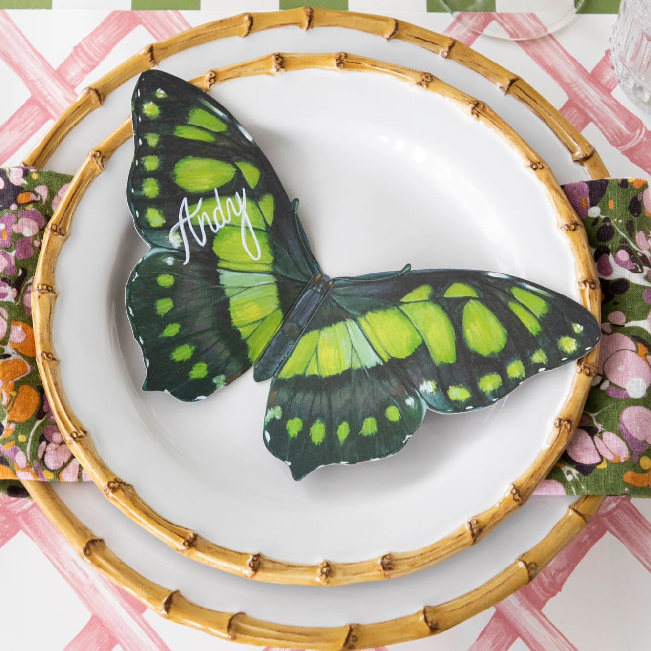 Butterfly Table Accent with "Andy" written in white ink on it, resting on bamboo dinner plates on an elegant place setting.