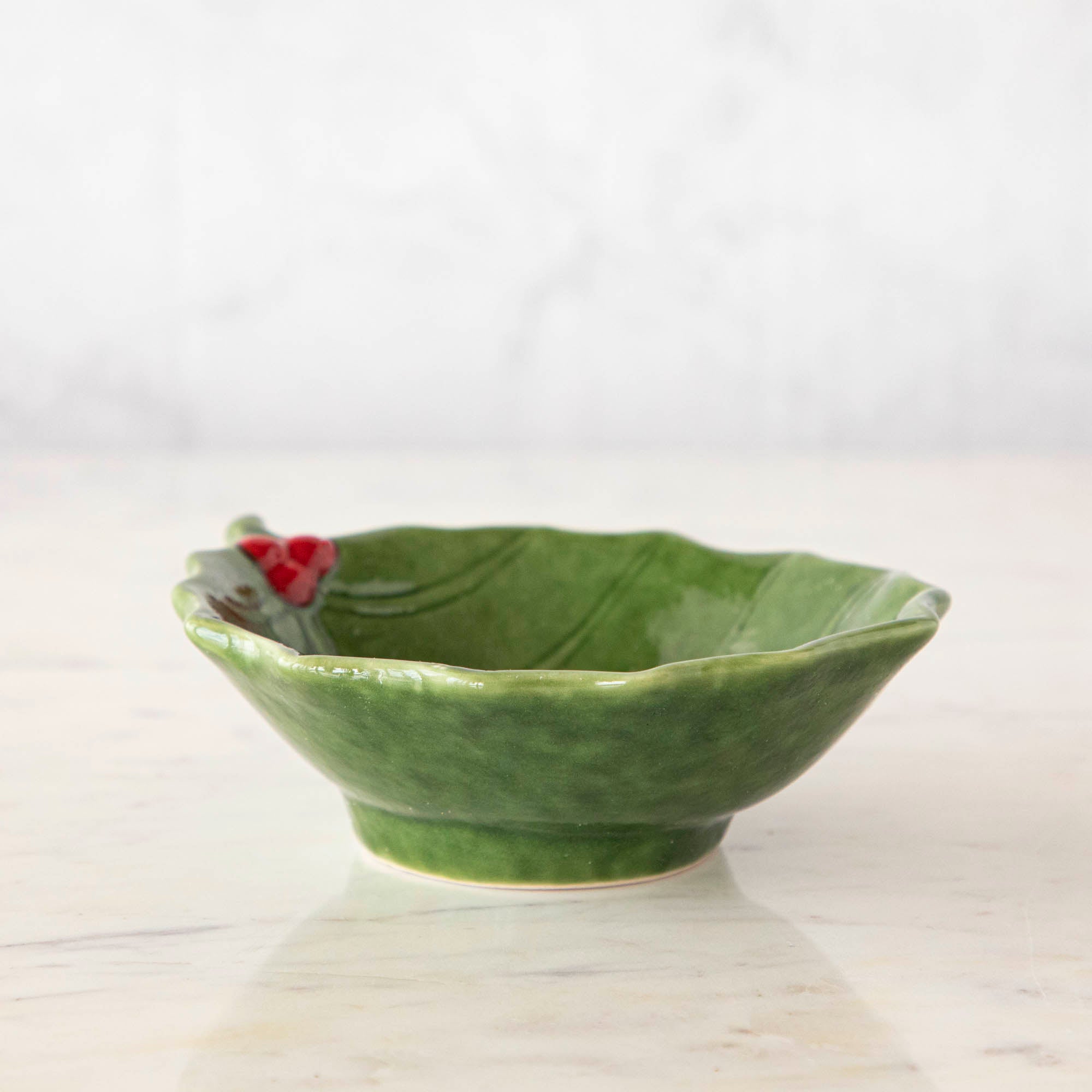 A green stoneware bowl with a holly leaf pattern.