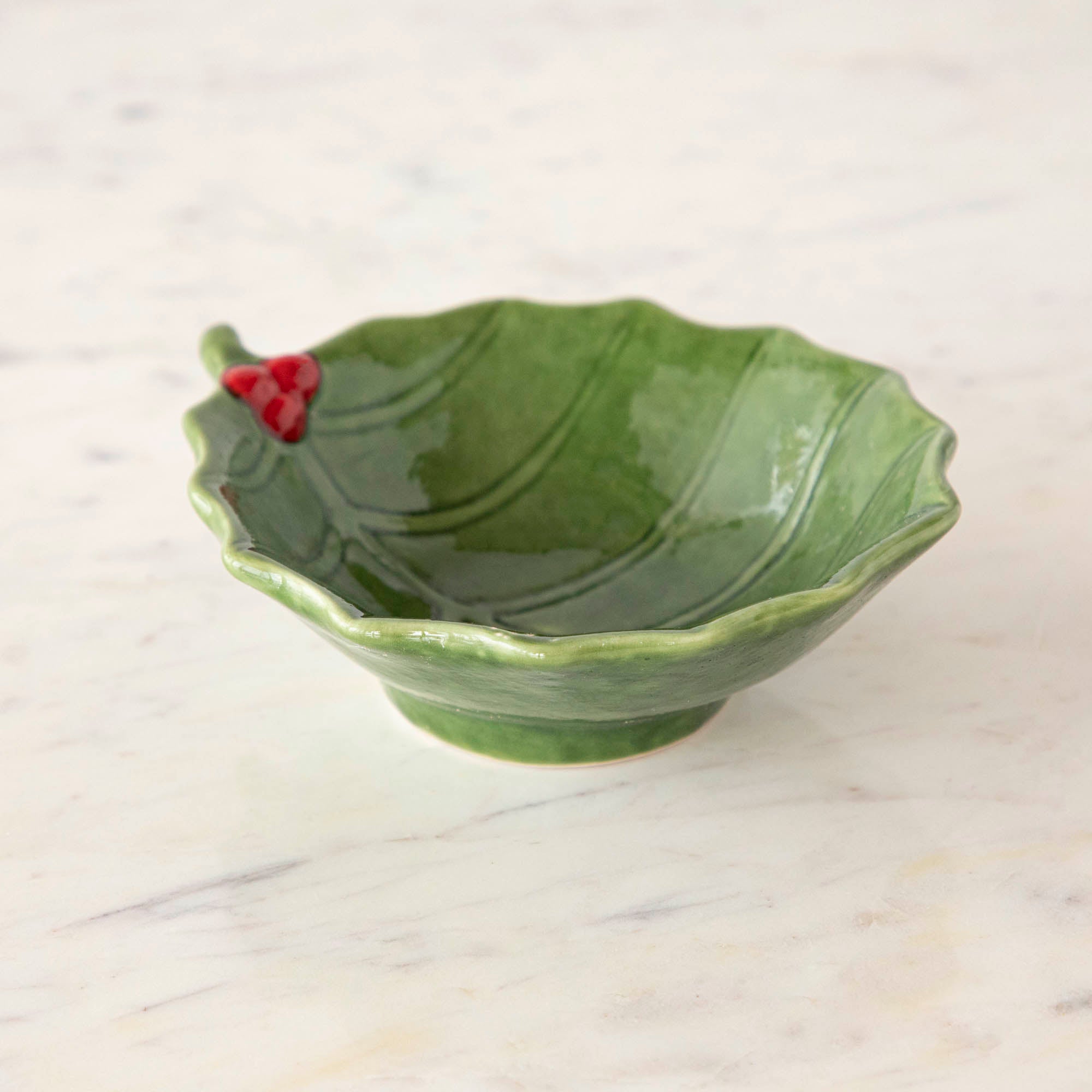 A green stoneware bowl with a holly leaf pattern.