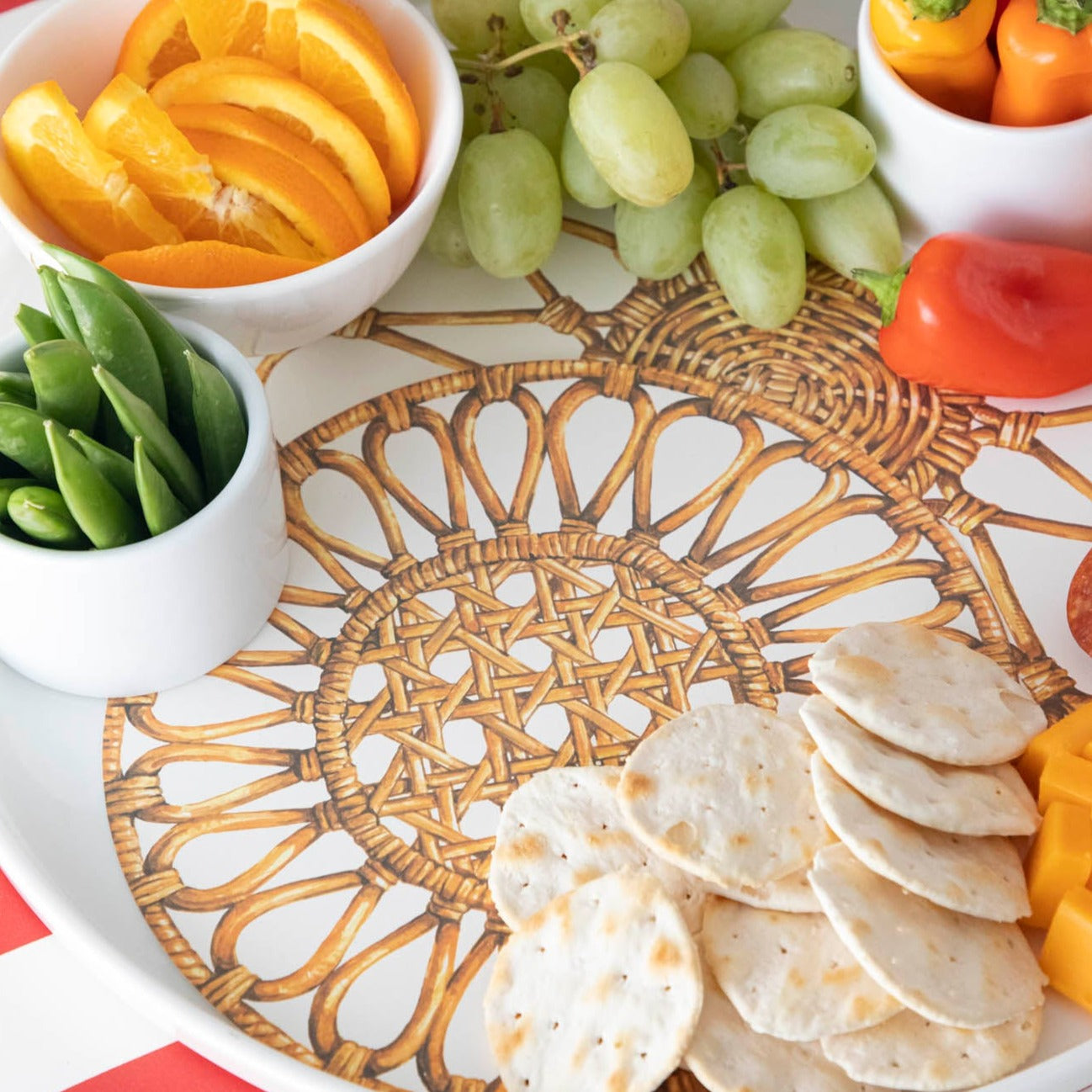Close-up of a Rattan Weave Serving Paper under fruit and crackers under an elegant charcuterie spread.