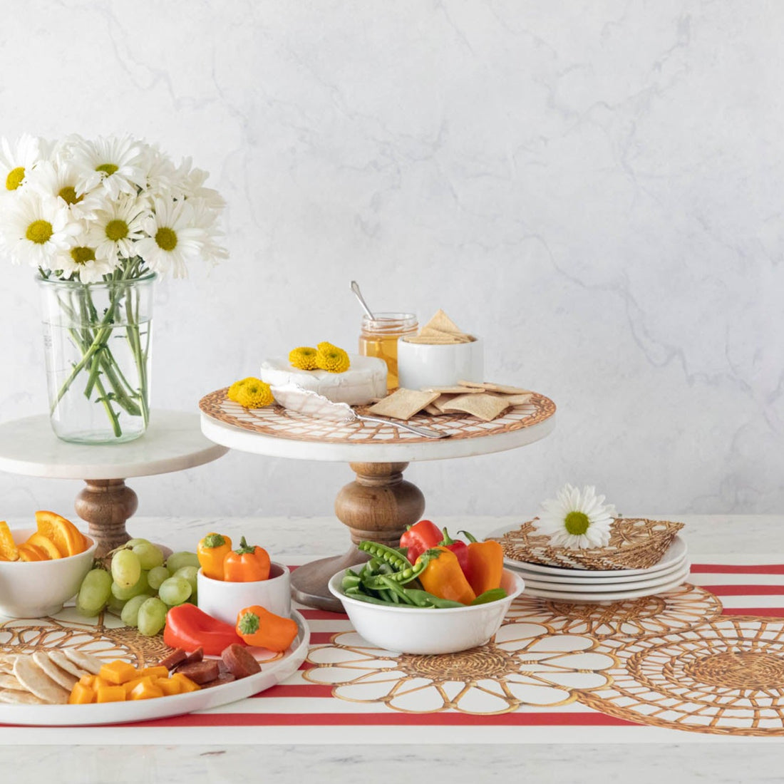 An elegant charcuterie spread with cake stands and a vase of flowers, featuring Rattan Weave Serving Papers.
