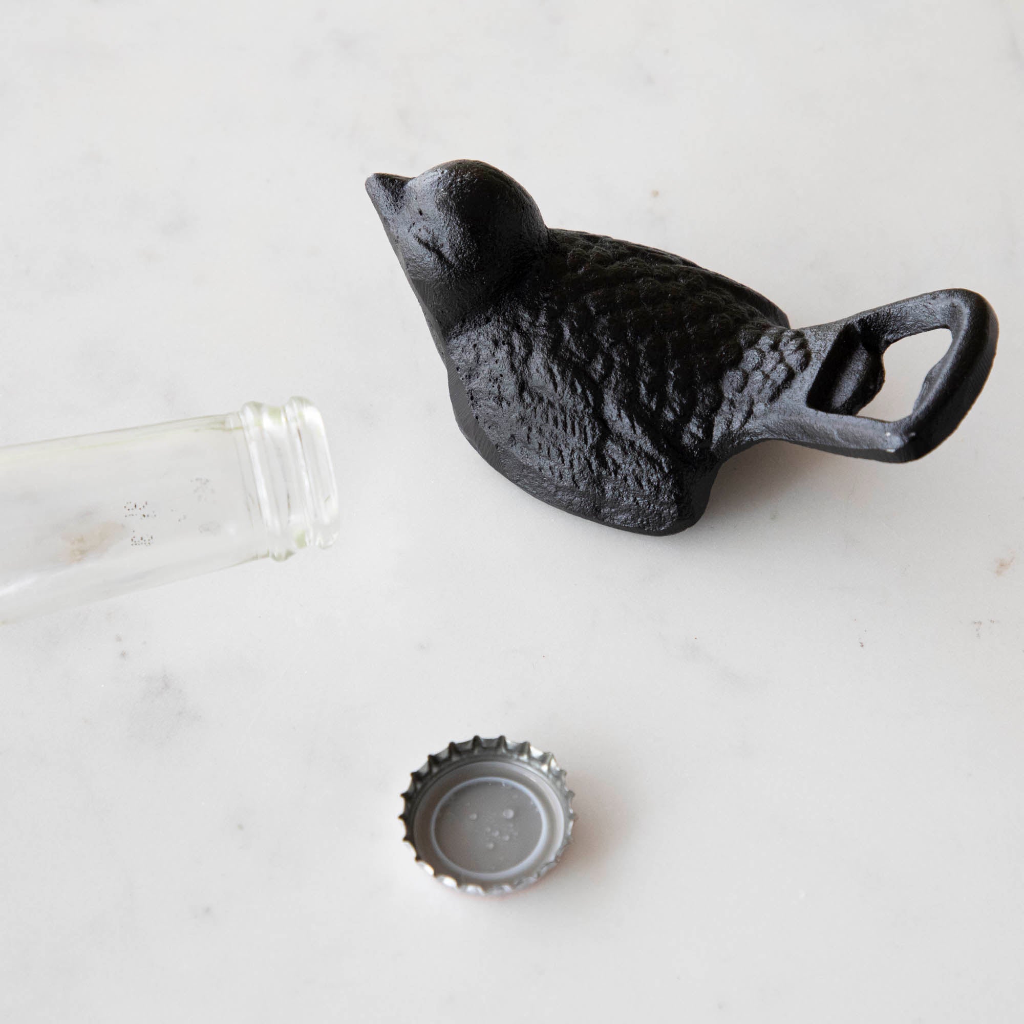A small Park Hill Cast Iron Bird Bottle Opener with a rustic cast iron finish is sitting on a table.