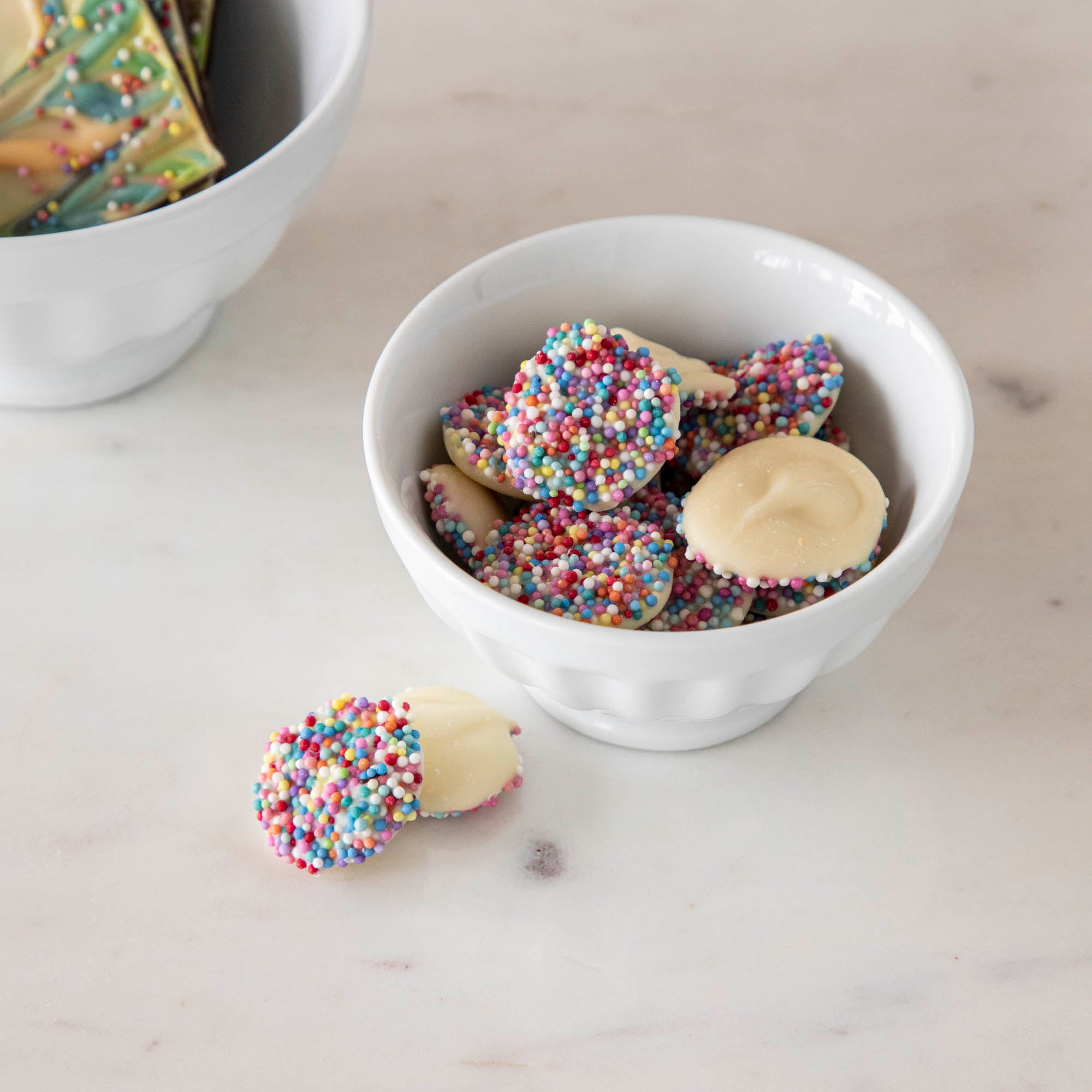 White Fluted Bowl with chocolate candies inside.