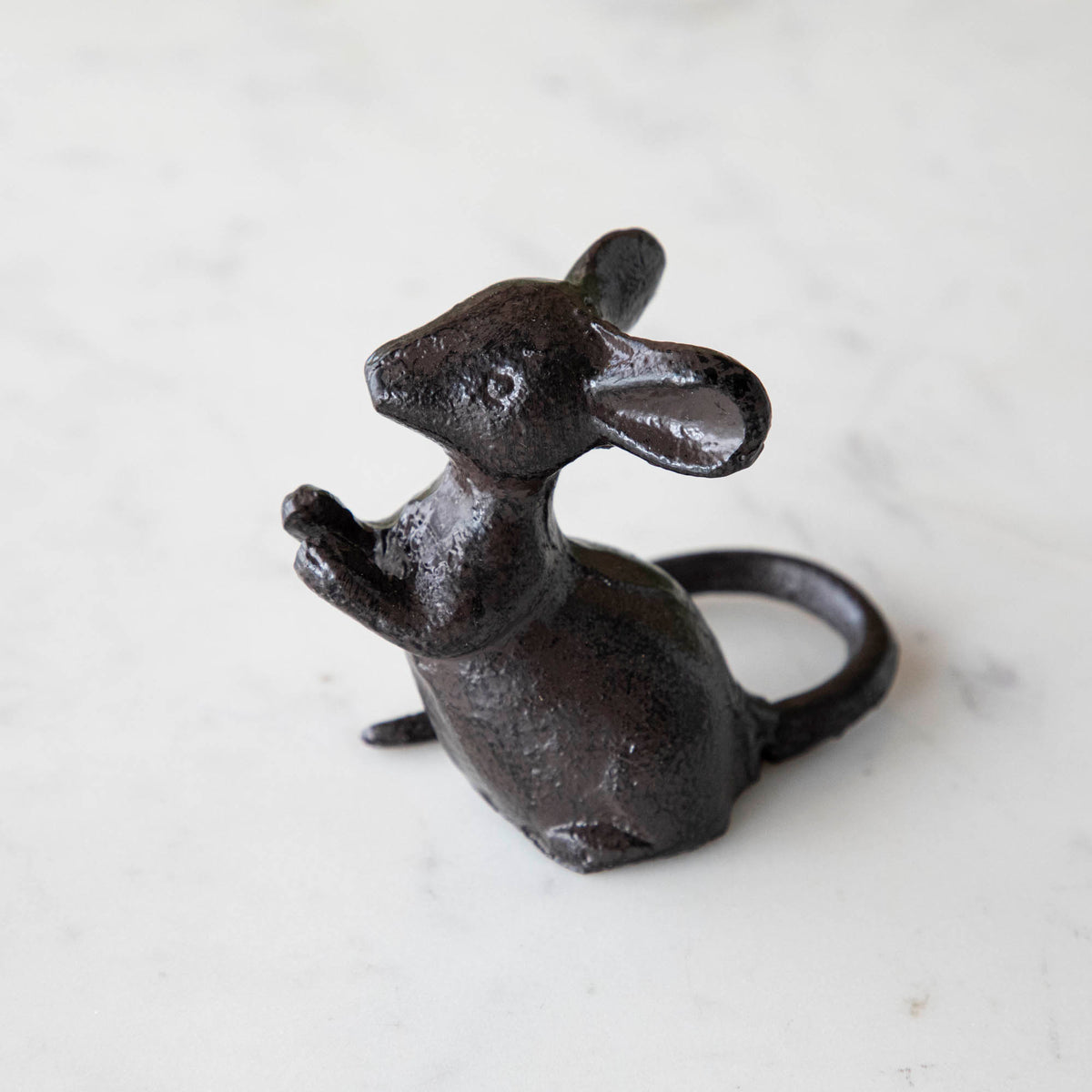 A cast iron mouse on a marble table.