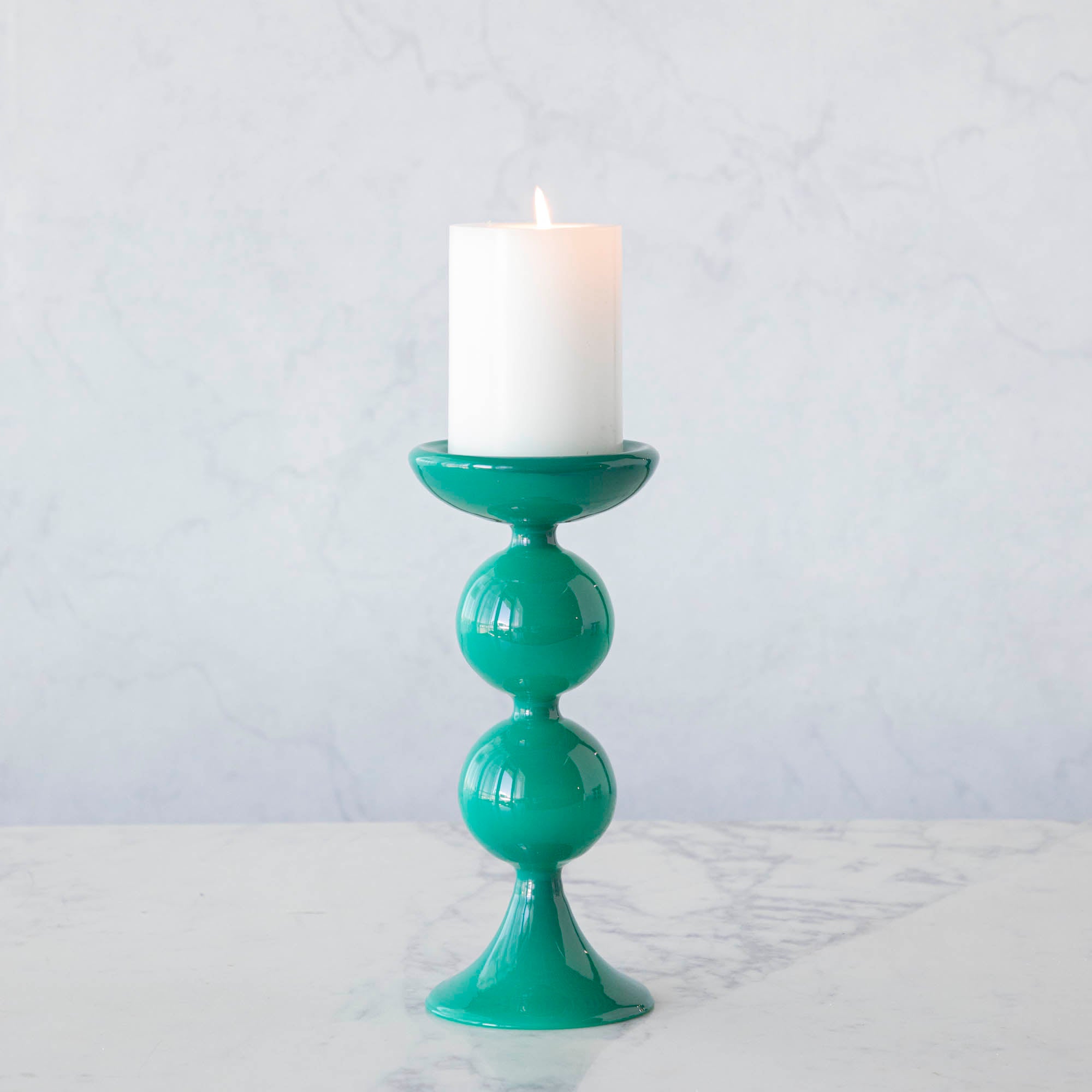 A group of Glitterville Sweet Bubble Pillar Candle Holders in vibrant colors with a candle in the middle.