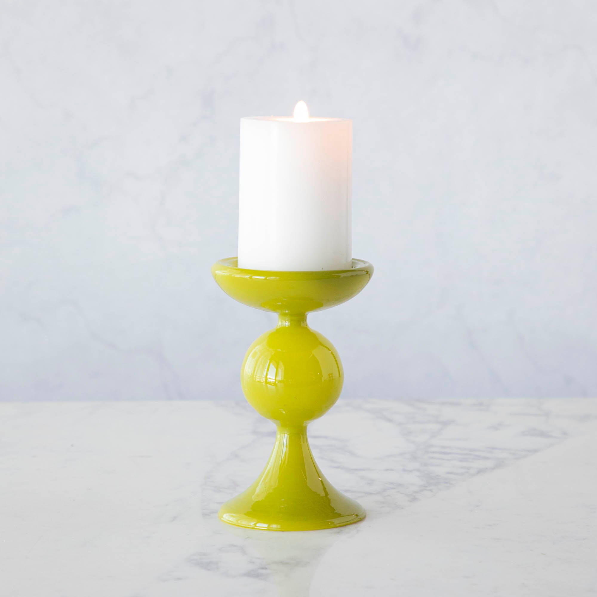 A group of Glitterville Sweet Bubble Pillar Candle Holders in vibrant colors with a candle in the middle.