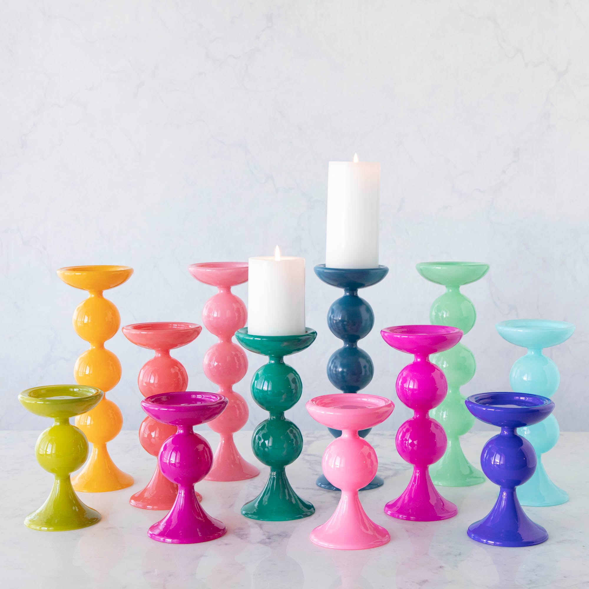 A group of Glitterville Sweet Bubble Pillar Candle Holders in vibrant colors with a candle in the middle.