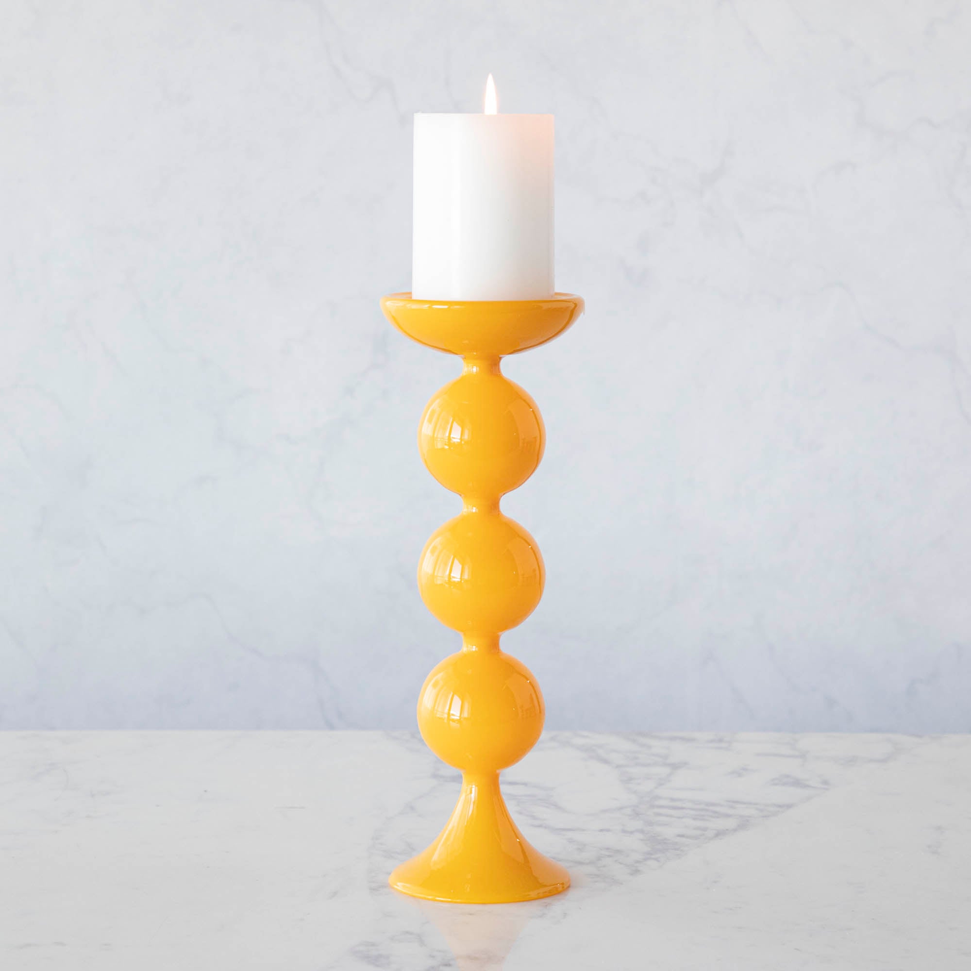 A group of Glitterville Sweet Bubble Pillar Candle Holders in vibrant colors with a candle in the middle.