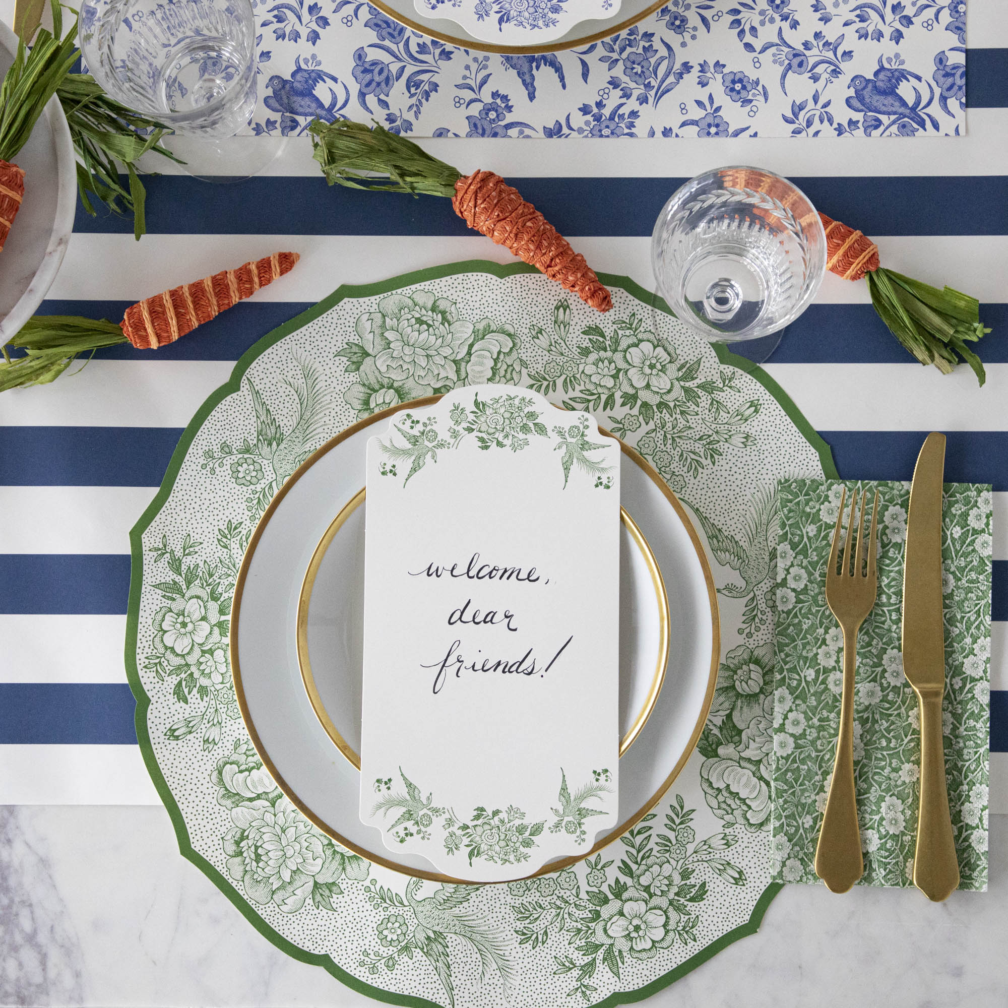 A Green Calico Guest Napkin under gold cutlery in an elegant place setting, from above.