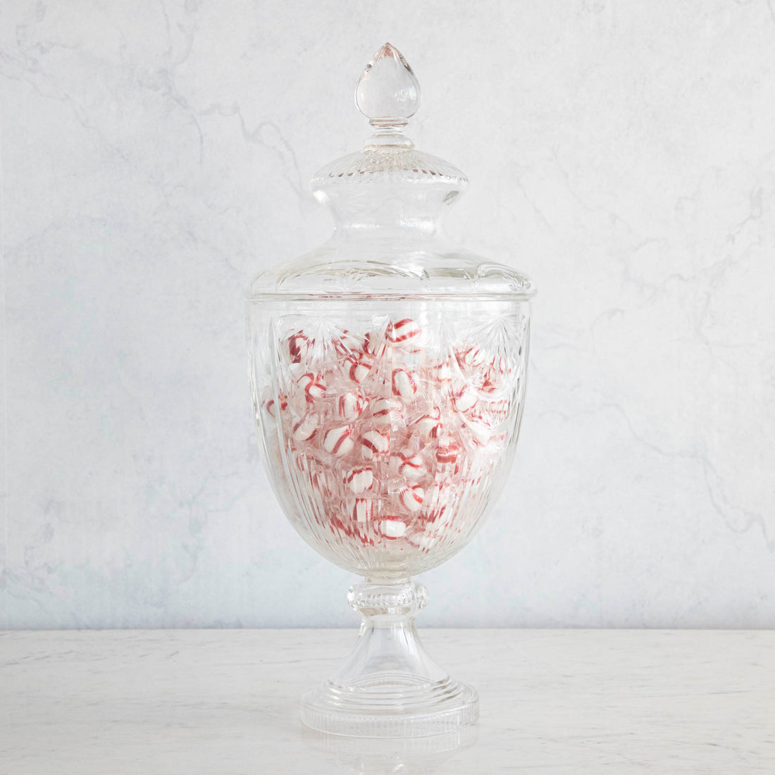 An elegant Shi Shi Glass Bonbonniere Vase filled with red and white candy canes on a marble background, showcasing its timeless design as a standout piece of home decor.