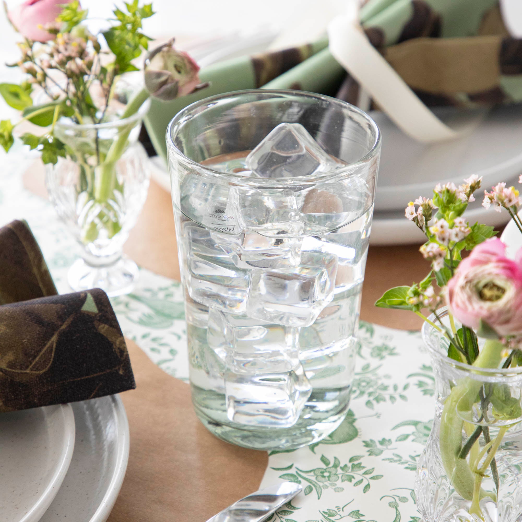 Three empty Margarida Recycled Glasses vessels of varying heights and shapes, made by Casafina Living, rest on a white surface.
