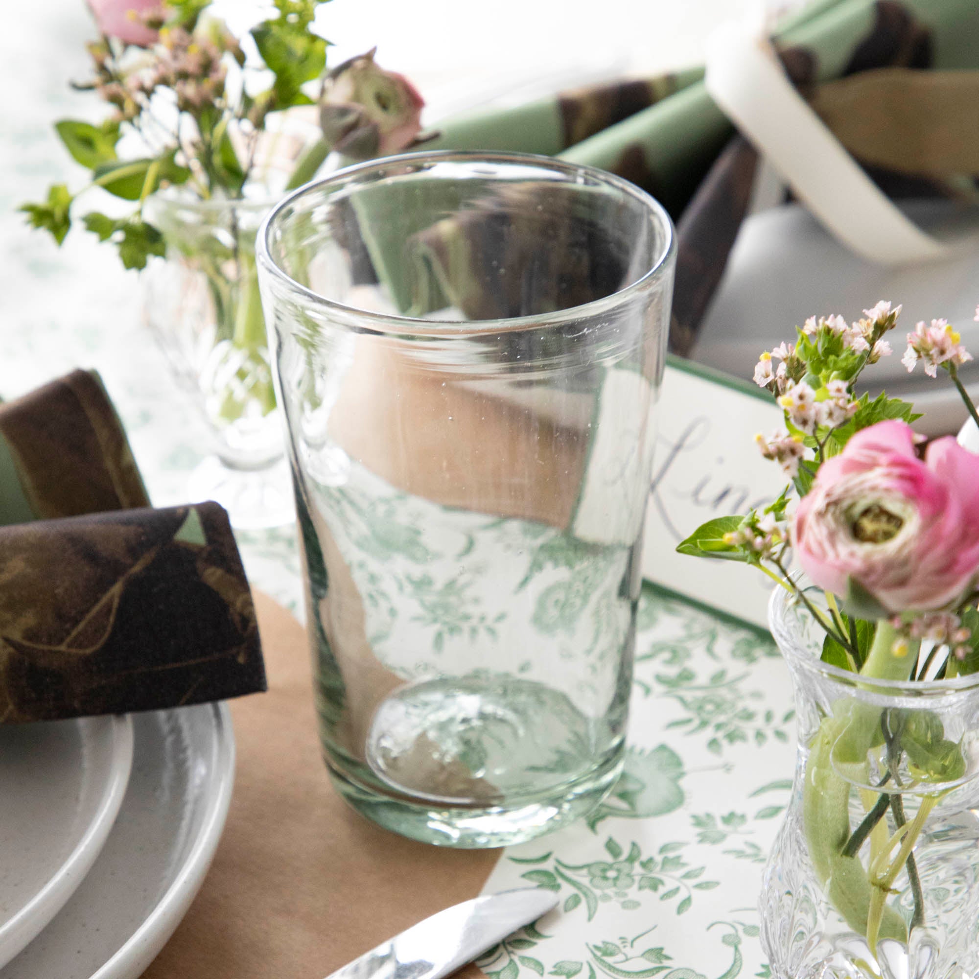 Three empty Margarida Recycled Glasses vessels of varying heights and shapes, made by Casafina Living, rest on a white surface.