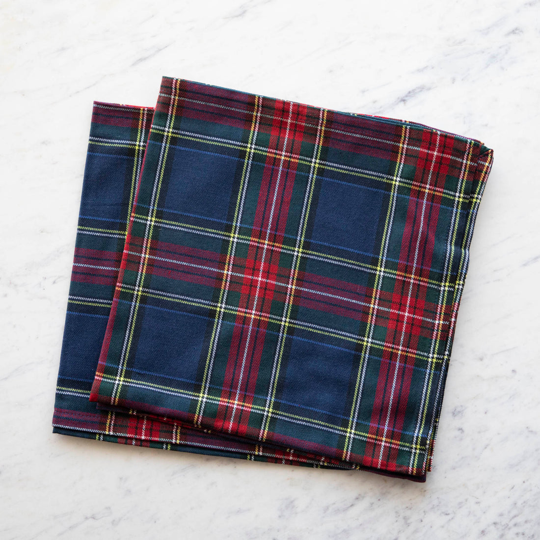 A plaid necktie with a windsor knot on a 100% cotton Taylor Linen Cape Breton napkin on a marble surface.