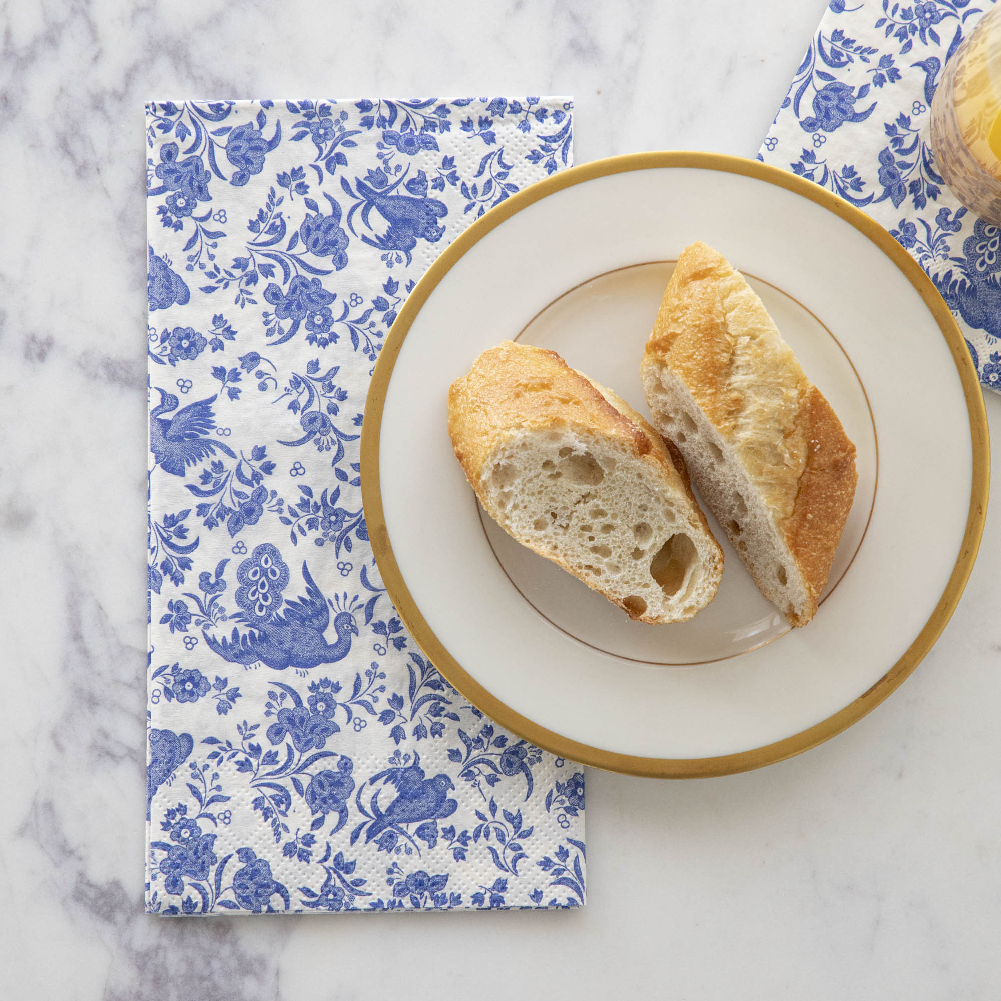 A plate of bread on top of a Blue Regal Peacock Guest Napkin by Hester & Cook.